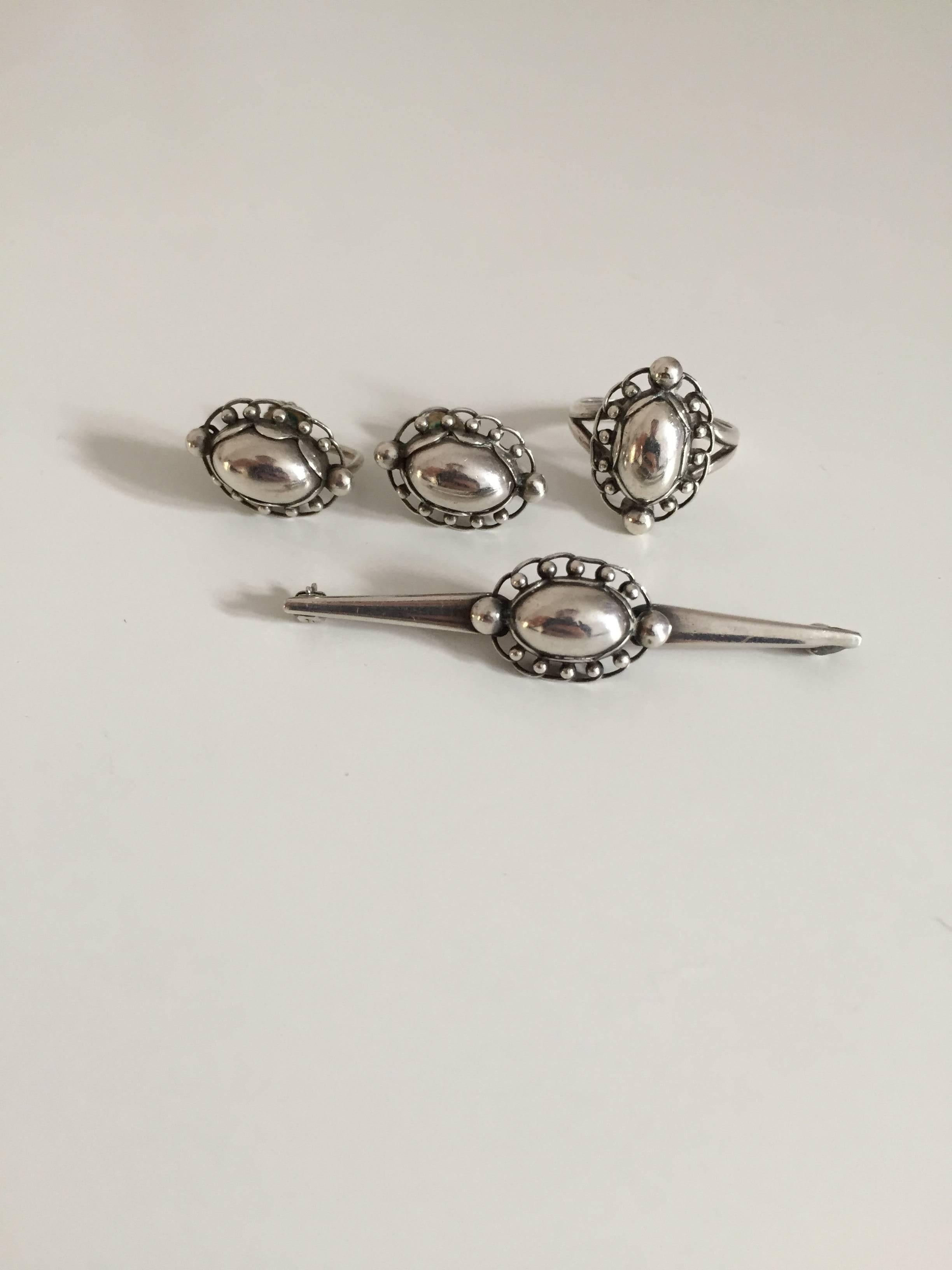 Georg Jensen sterling silver jewelry set of ring #21, brooch 195 and earclips #81.

Measurements: Ring size 55 1/2. Brooch 6.1 cm L. Earclips 2 cm x 1.1 cm.