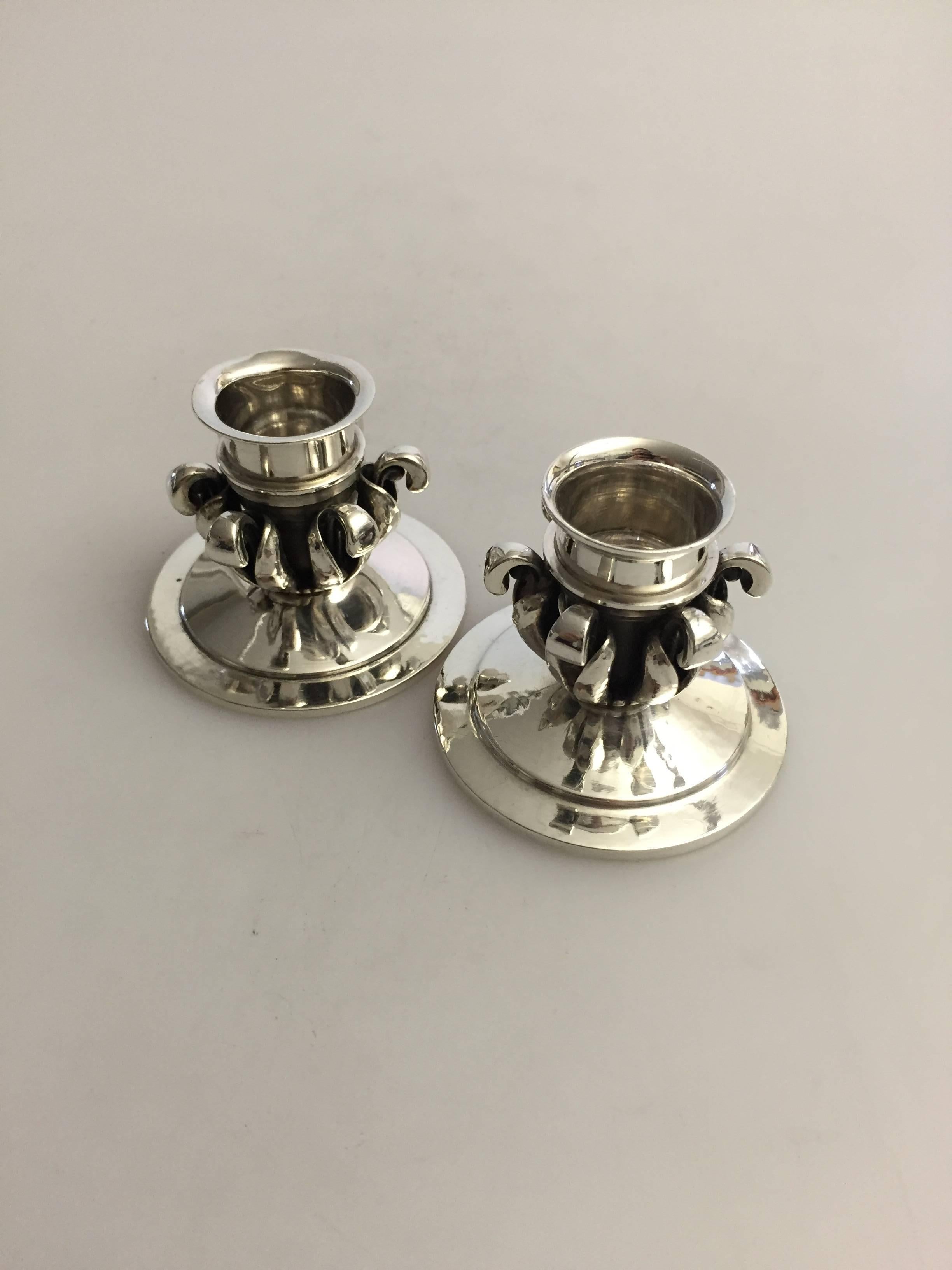 Georg Jensen pair of sterling silver candlesticks #598. There is a tiny height difference between the two, but it is hard to see with the visible eye. 

Measures 5 cm high and 6.2 cm in diameter.