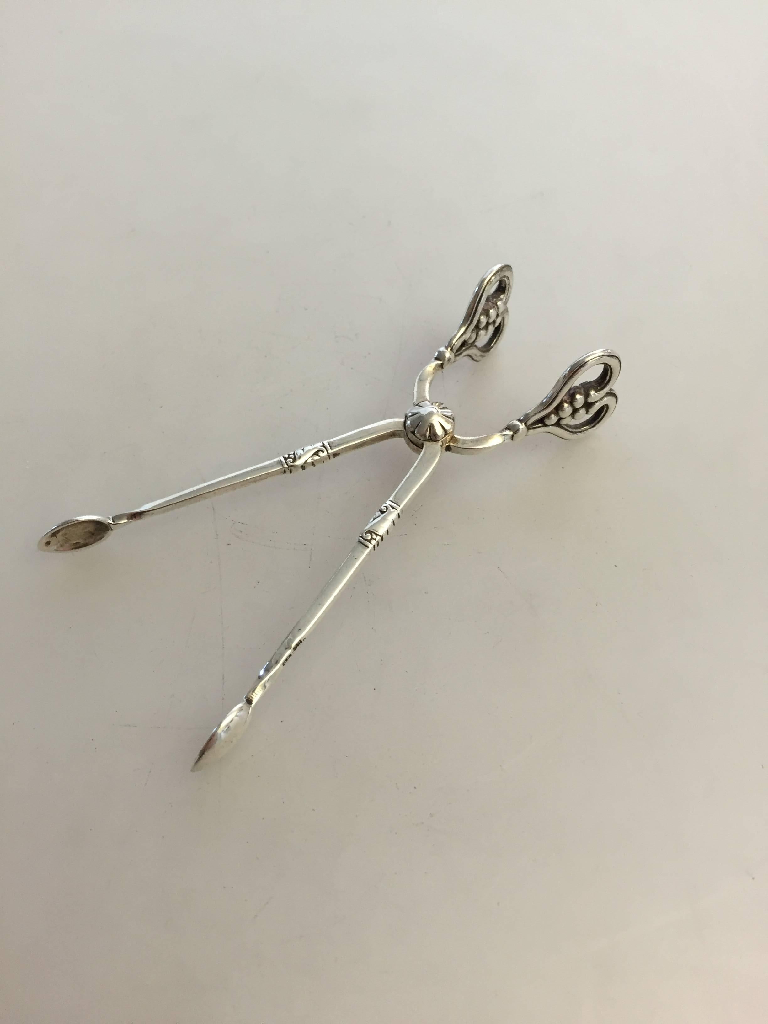 Georg Jensen sterling silver ornamental sugar tongs from 1915-1930. 

Measures: 10 cm L.
Weighs 0.90 oz/26 g.