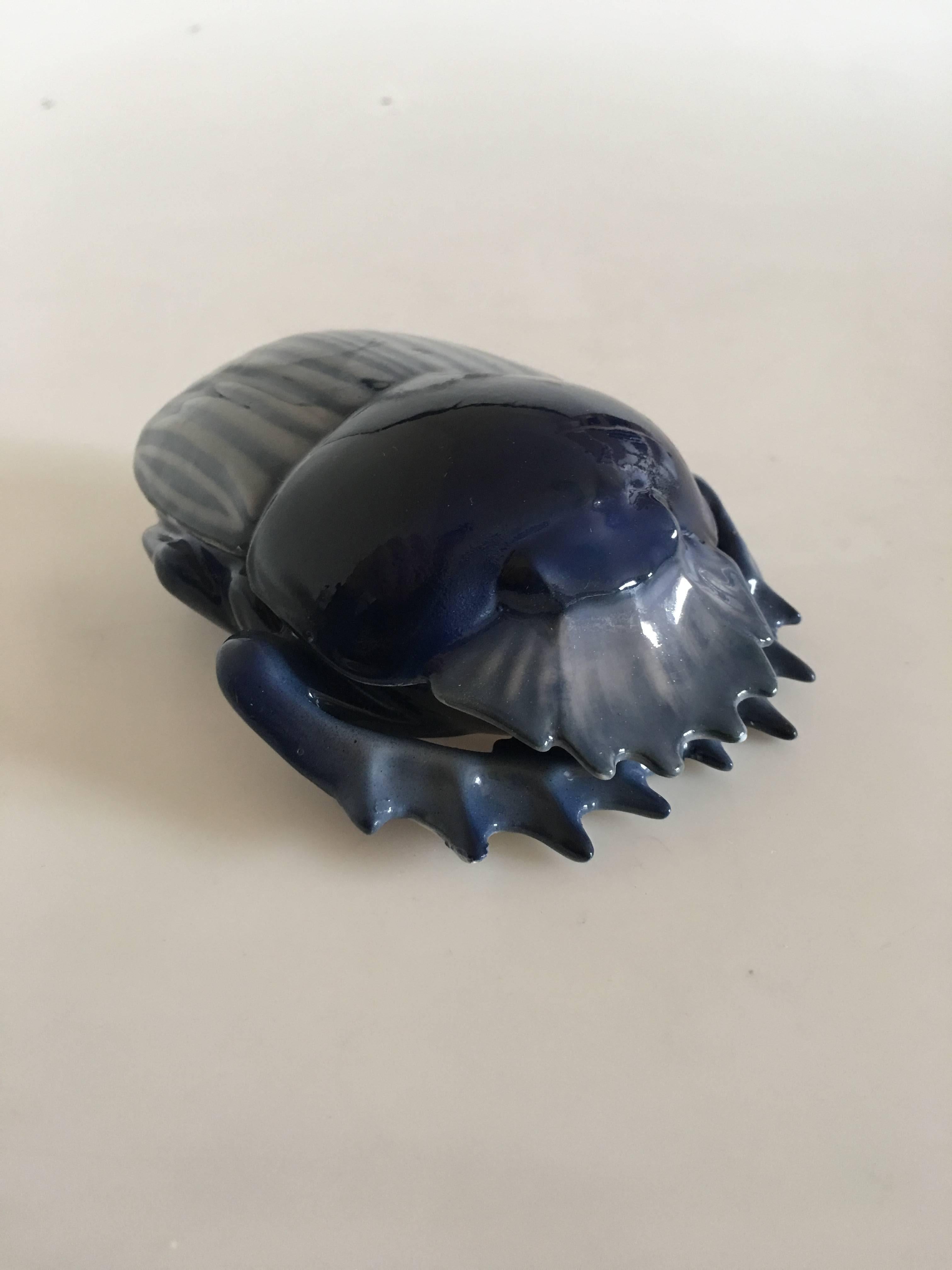 Royal Copenhagen scarab shaped lidded dish #31/16. In somewhat mate and shiny blue toned glazing finish. In beautiful whole condition. Measures: 12 x 10 cm (4 32/32