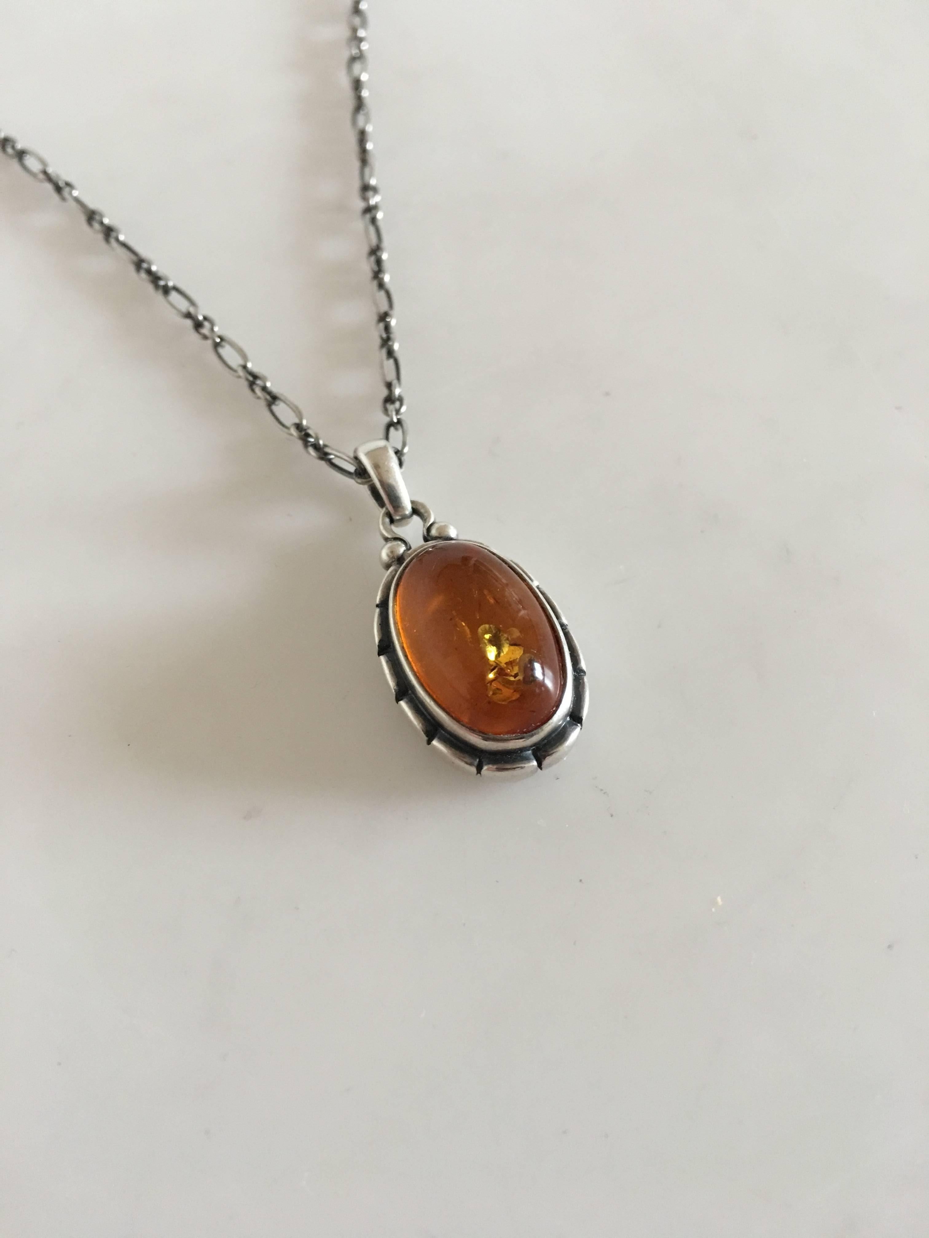 Georg Jensen annual pendant in sterling silver with amber stone, 2001. Chain measures 45 cm L. Pendant measures 2.4 cm. Chain and pendant measures 12 grams (0.40 oz).