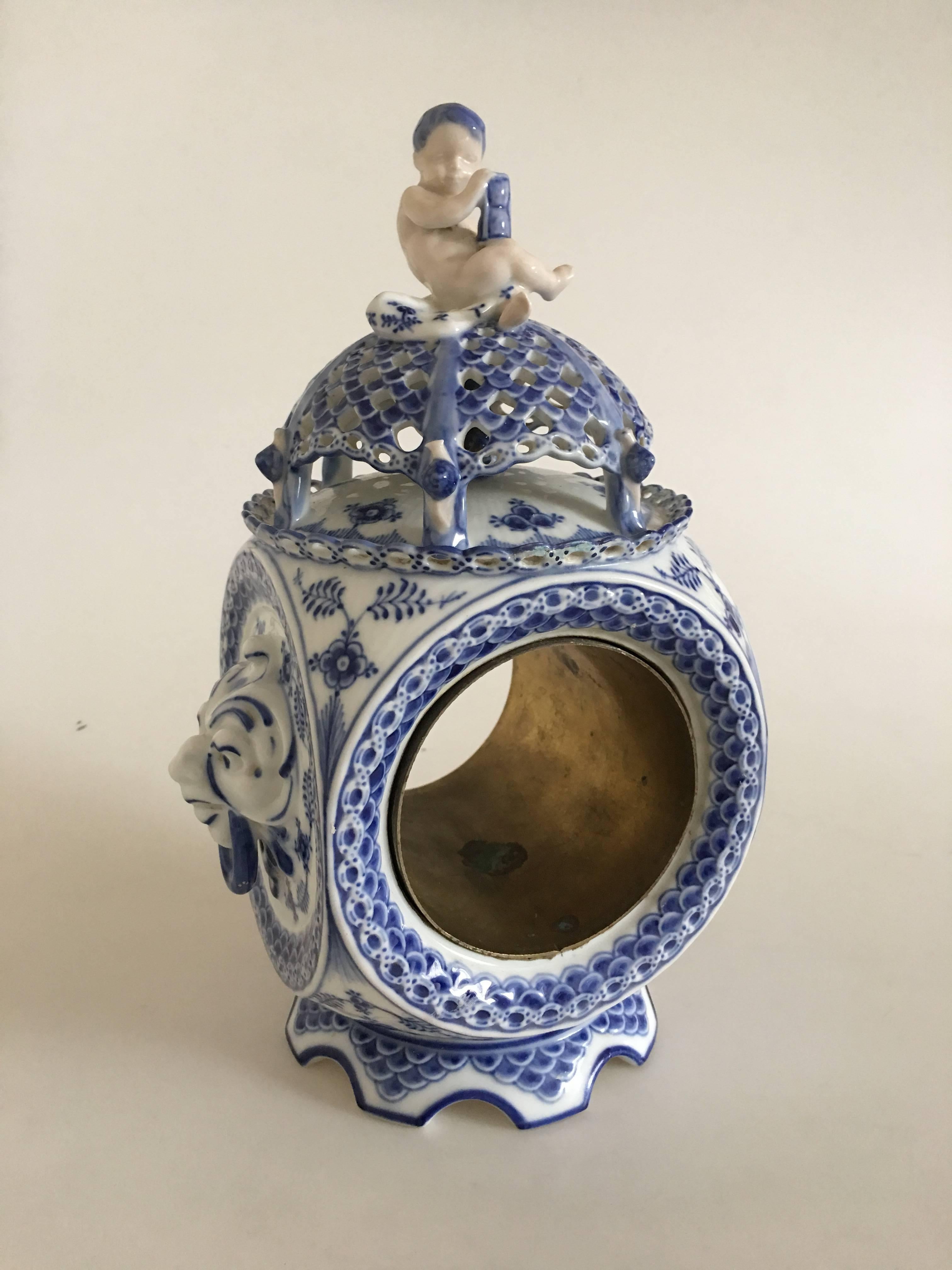 “Blue Fluted Full Lace” porcelain clock decorated in underglaze blue. Royal Copenhagen 1017, end of 19th century. Measures: H. 28 cm. The clock has larger repairment at the bottom foot piece, and a minor in comparison on the top lace border. Look at
