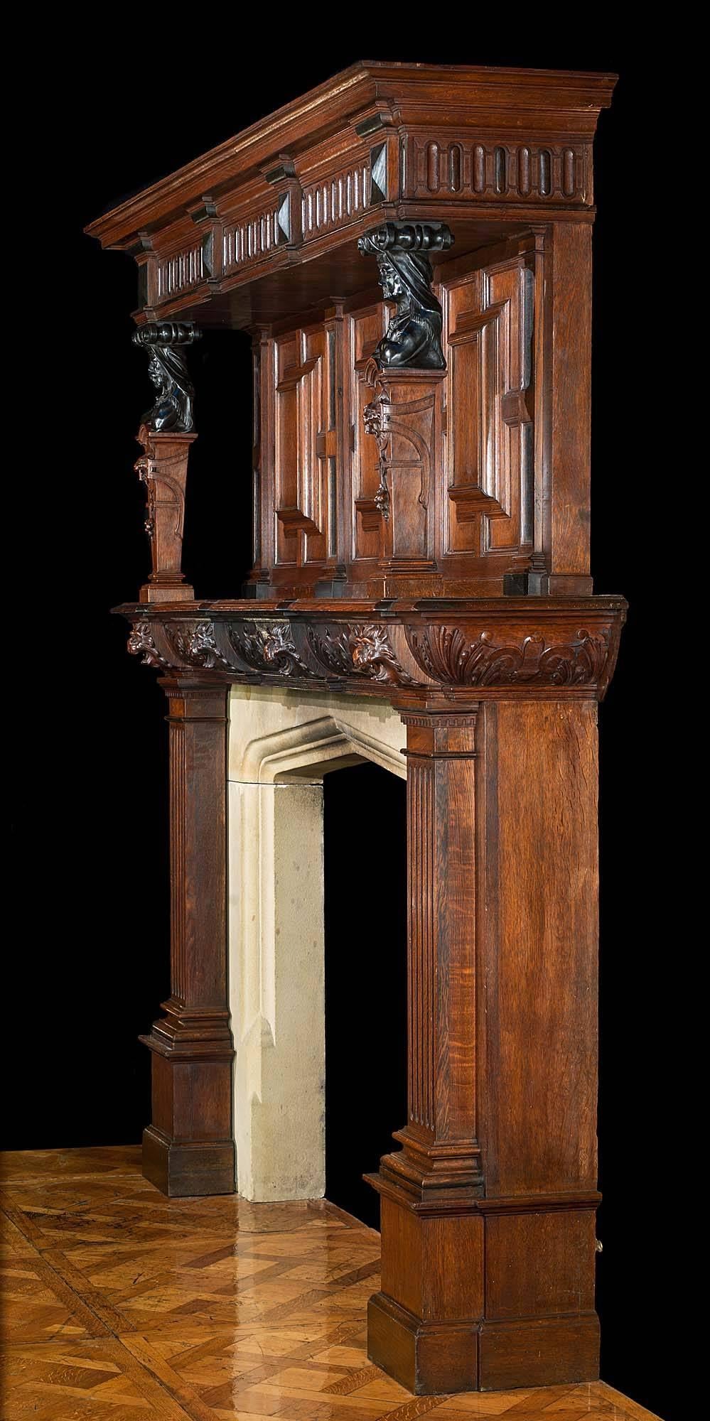 A large antique Jacobean style carved oak chimneypiece and overmantle. The strap work barrel frieze is divided by well carved lion masks, mirrored on the end blocks, above the simple fluted pilaster jambs with dental capitals, supported on tall