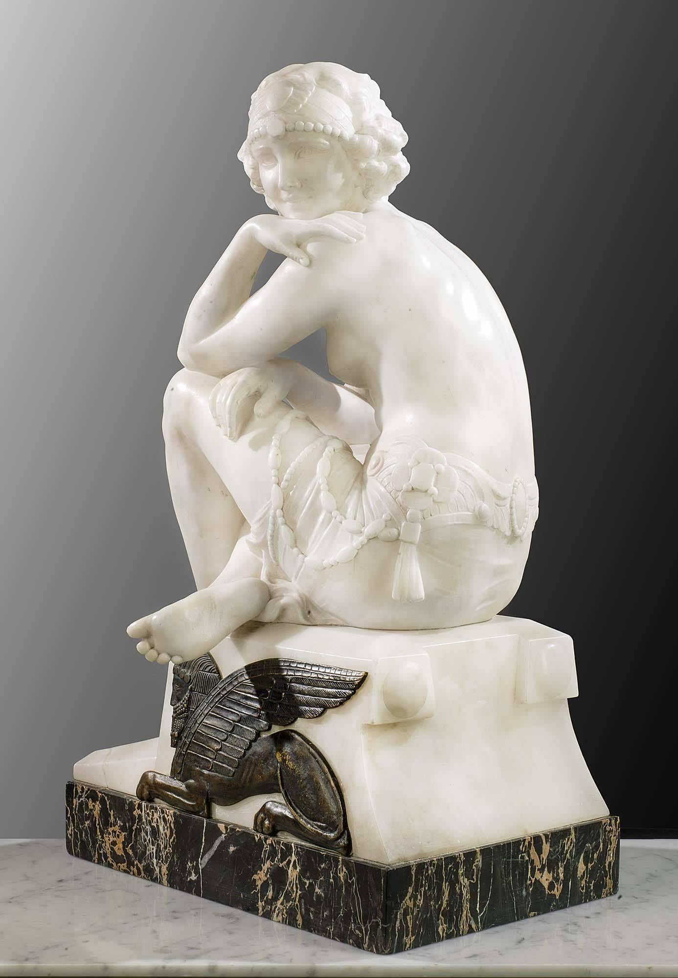 Beautifully carved in statuary marble, this Art Deco figure of a woman rests on a portoro marble base, set with a patinated brass sphinx. The figure wears beaded drapery and a jewelled diadem. 

The statue bears the signature, L Morelli,