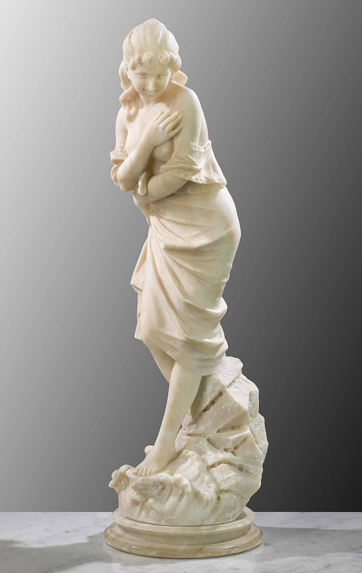 An antique Italian carved Alabaster figure of a young bather standing on a rusticated base of rocks, lapped by waves, and resting on a circular moulded plinth. Some minor scuffs and scratches,
Italian, late 19th century.
     