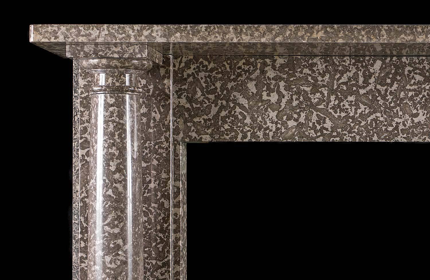 An elegant Regency columned chimneypiece in warm grey fossil marble reminiscent of a leopard's coat. The Doric columns stand free of the jambs and support the simple shelf set above the unadorned frieze.

English, circa 1810.
 