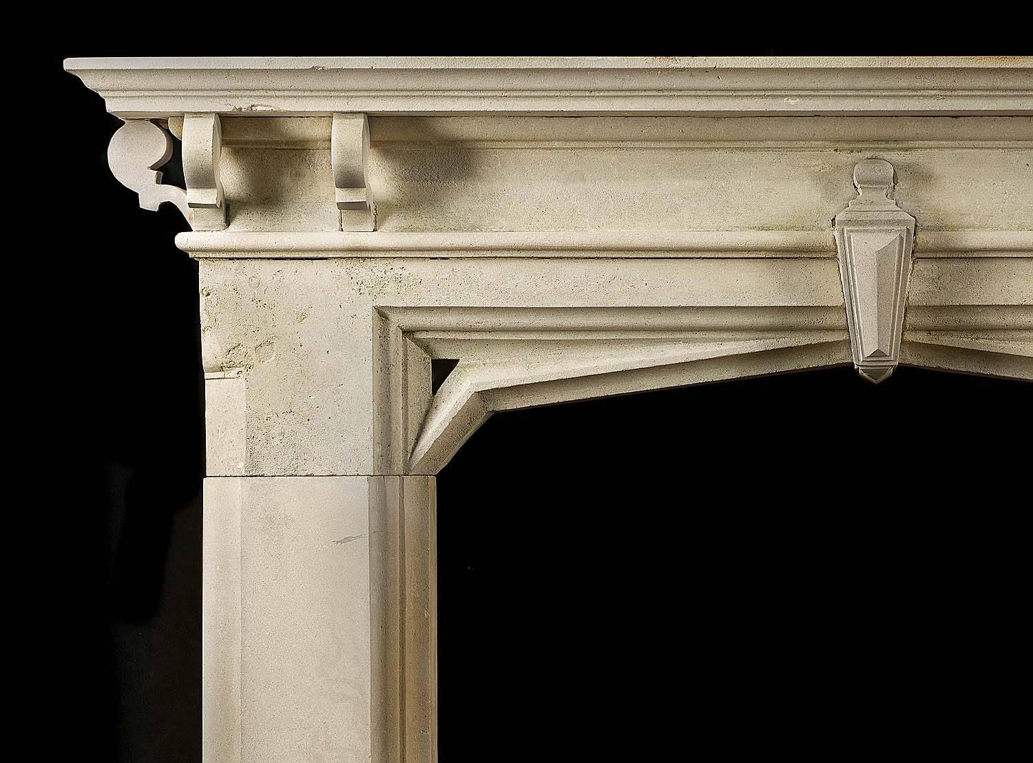 A Victorian Gothic Revival limestone antique fireplace surround with a small central keystone linking the frieze to the arched opening and a shelf supported on six small brackets.
English, mid-19th century.