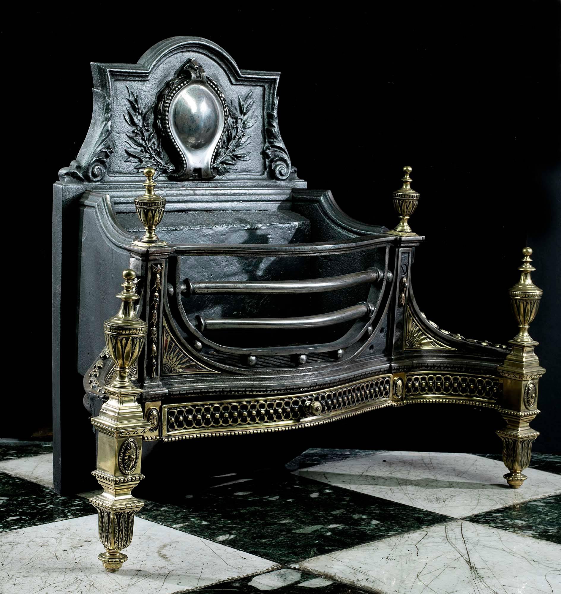 An elegant serpentine fronted cast iron and brass antique fire grate in the late Georgian manner of Robert Adam. The cartouche relief on the fire back is flanked by olive branches and scrolled acanthus. The barred grate, sits above a pierced apron