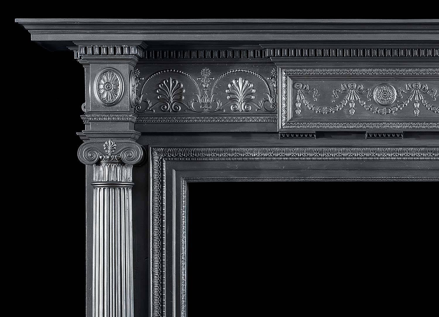 A high and handsome large antique Coalbrookdale cast iron Victorian fireplace surround with an athemion decorative frieze centred by a plaque with swag and medallion in the neoclassical style. The wide shelf above a dentil border rests on a pair of