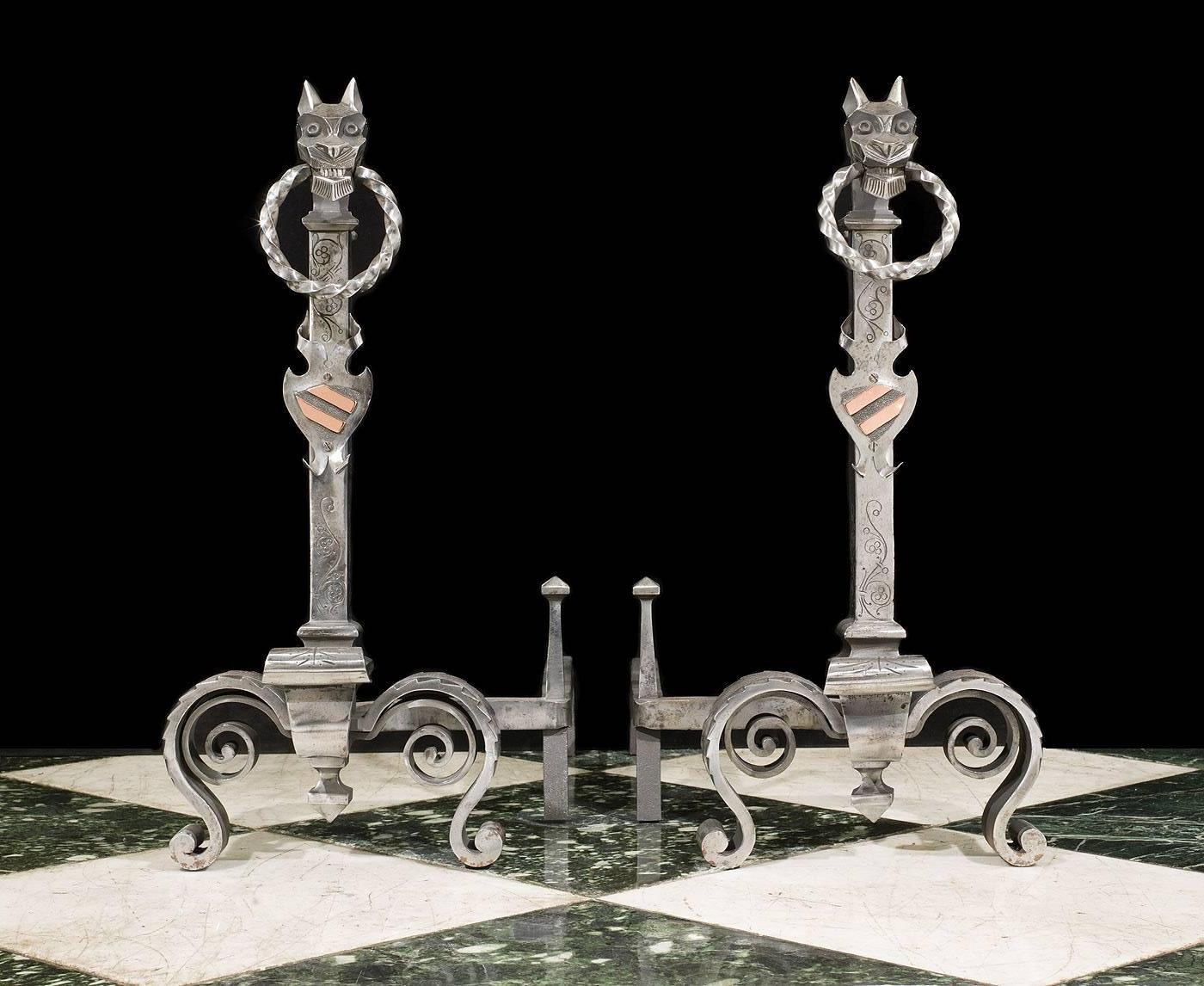 A pair of tall Gothic style wrought iron andirons. The florally etched standards,
topped by a pair of wolf heads holding rings in their mouths above stylized
shields, are supported on foliate decorated scrolled and splayed feet.
Swan's nest