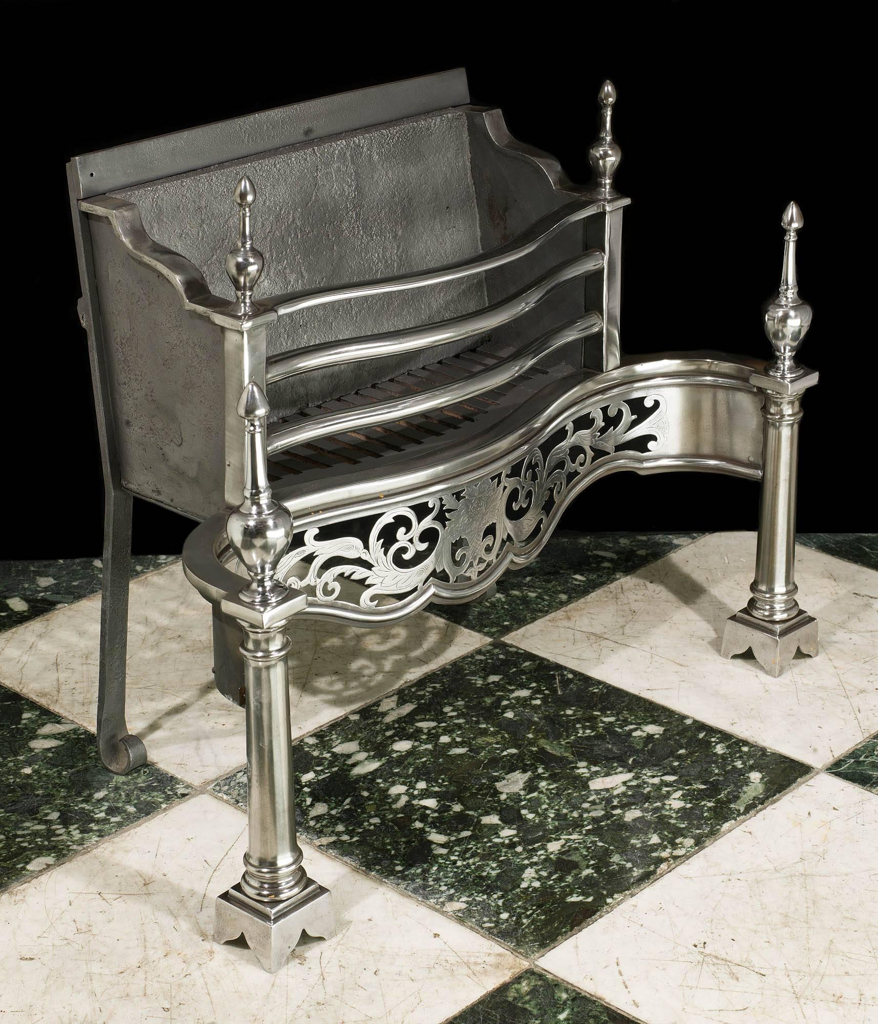 A George III style three barred polished steel fire basket surmounted by a pair of spire finials above a deep, engraved and pierced serpentine apron with a further taller pair of spire finials on the faceted columned standards.

English, late 19th