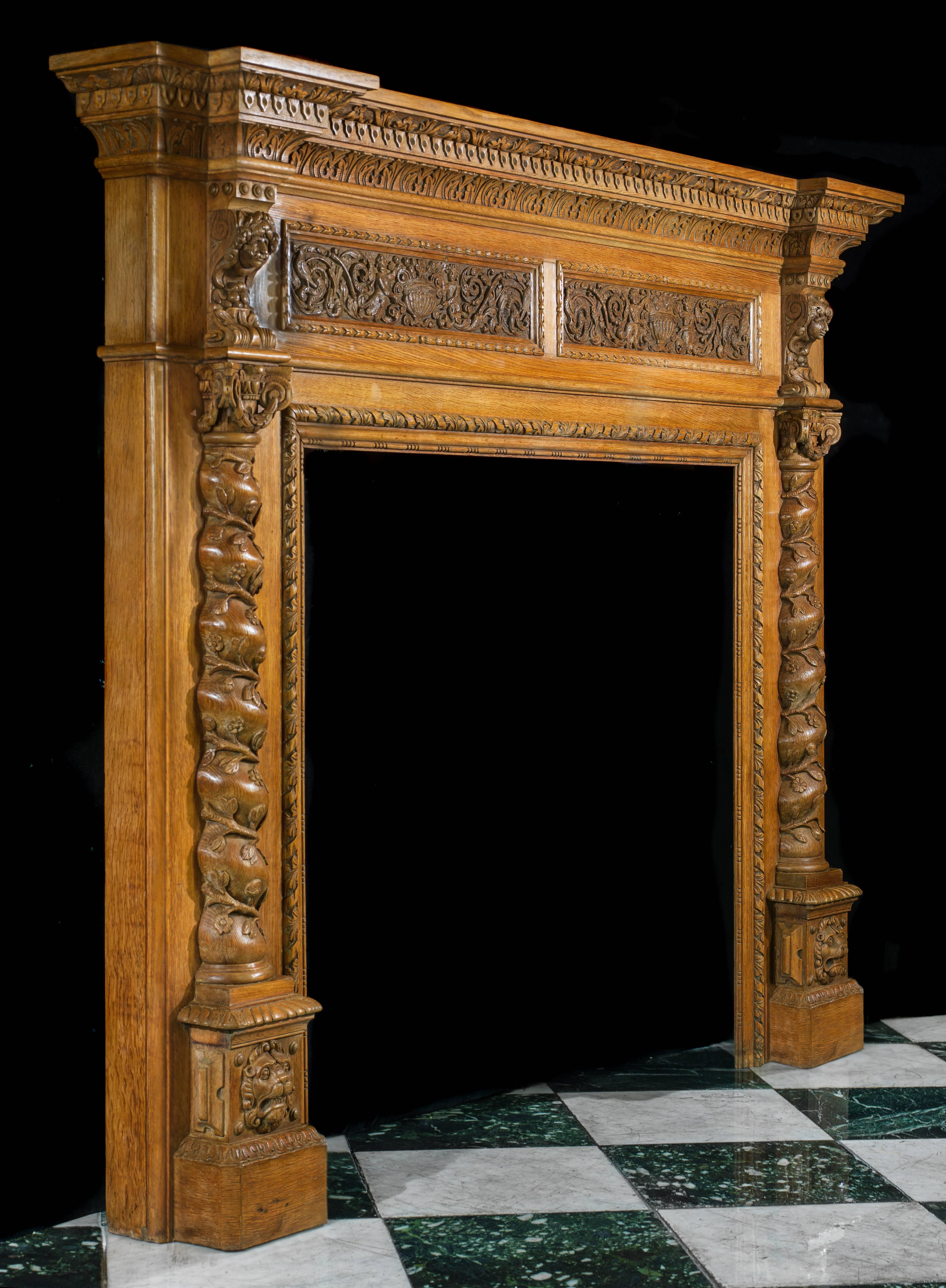 A large carved oak fireplace surround in the Italian Renaissance manner. The breakfront shelf with carved decoration over the frieze inset with twin carved panels of putti holding urns amidst scrolled ornament. The figural endblocks are supported on