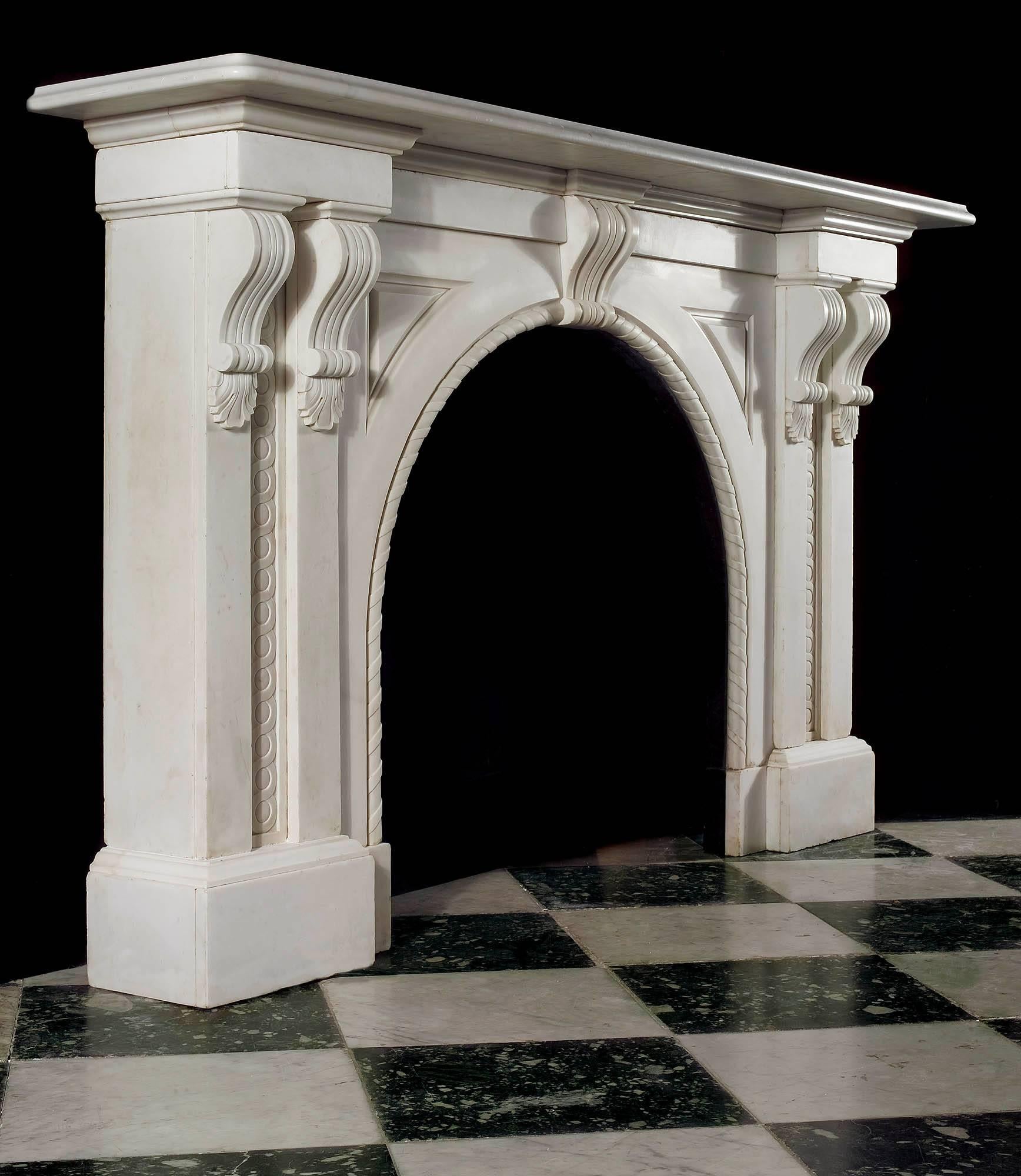 A large and imposing Victorian arched fireplace carved in white statuary marble. The massive plain moulded shelf is supported on twin scrolled corbels descending into twin pilasters each side with carved guilloche motif inset in the panels, either
