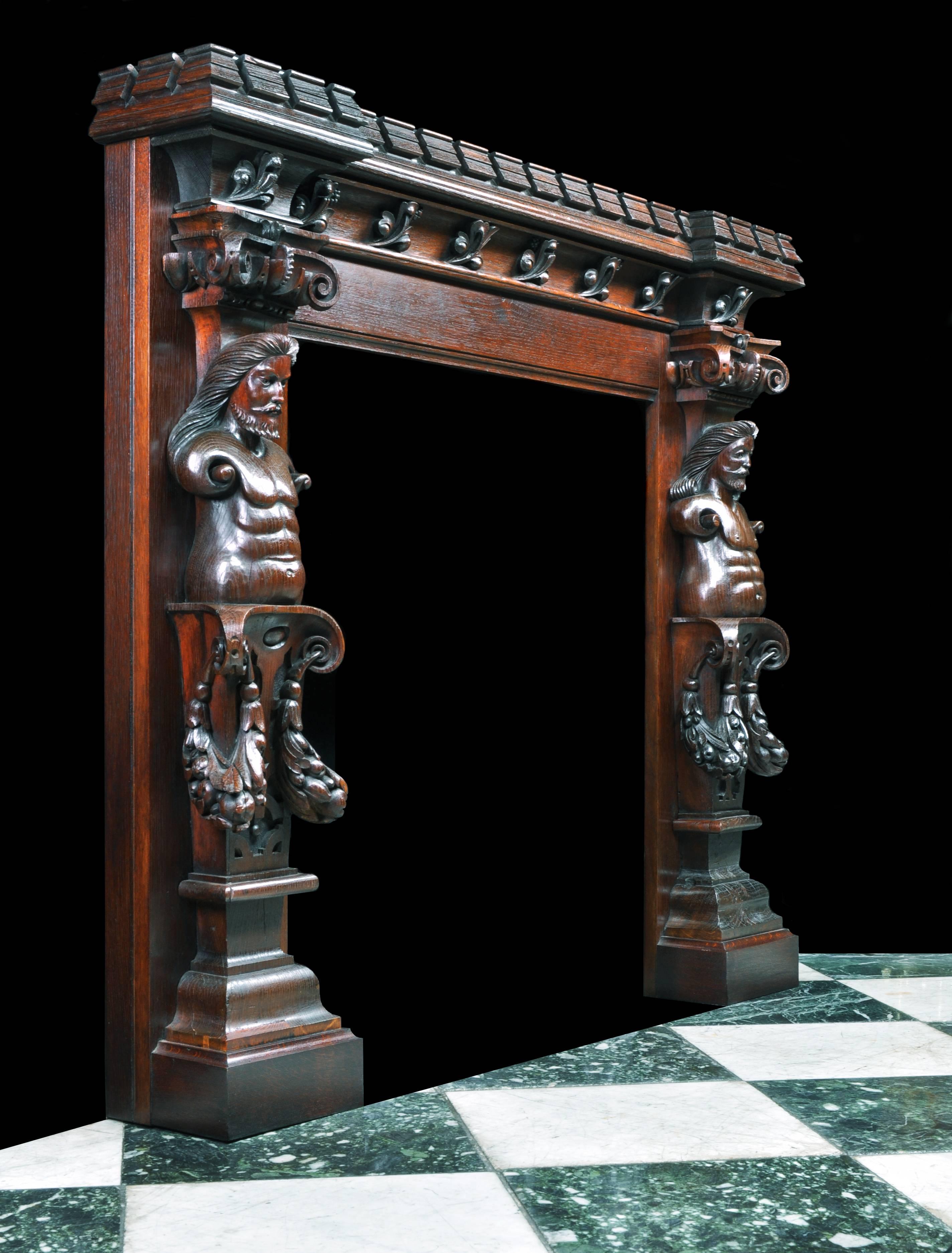 A small decoratively carved oak fireplace in the Jacobean Revival manner with a substantial castellated shelf and later top, bold carved leaf adornment on the frieze, a pair of bearded caryatid on the jambs, supported on acanthus leaved and swaged