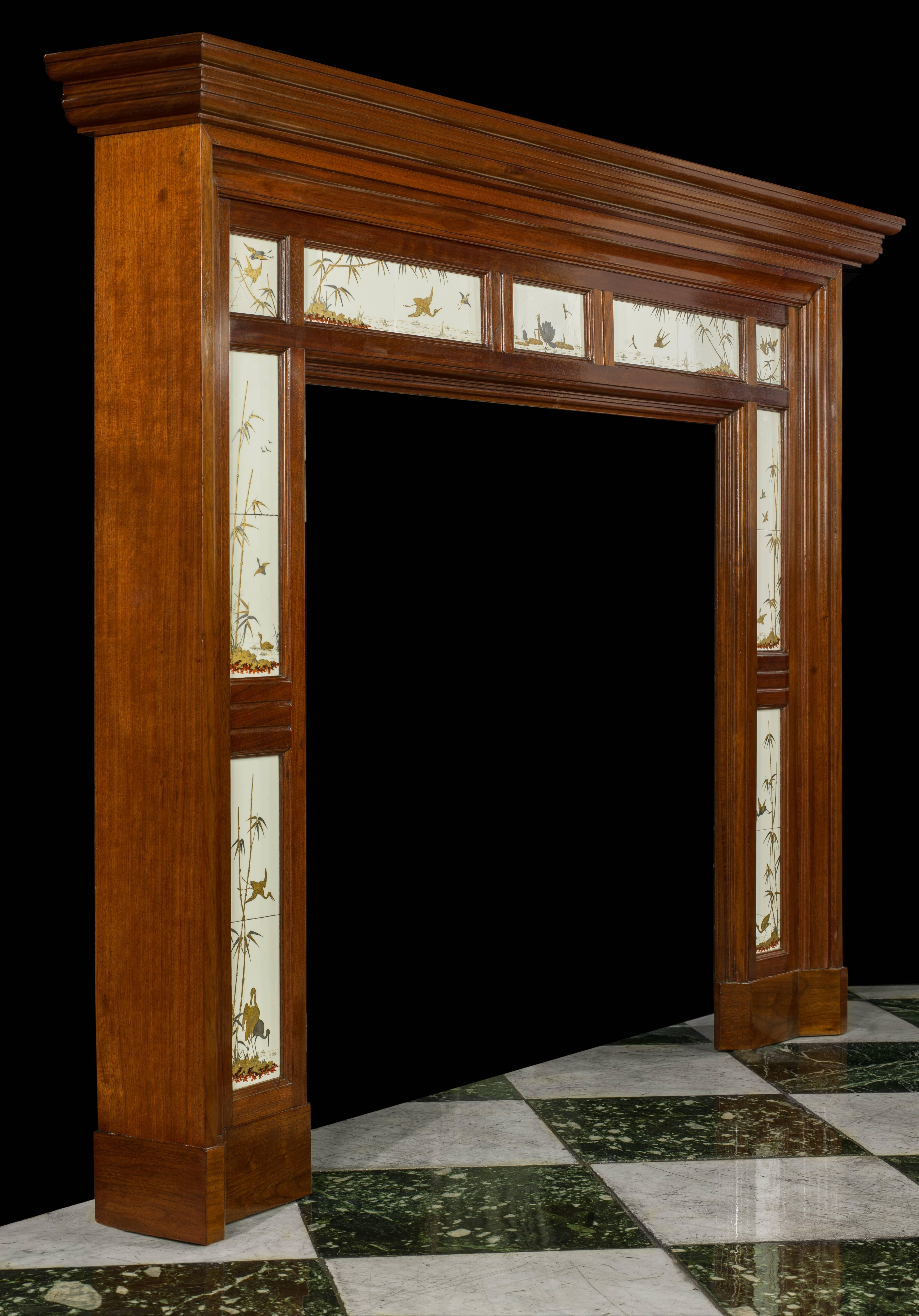 A simple panelled walnut fire surround set with very fine and rare Aesthetic Movement Tiles made by Minton & Company (1828-1868).

The tiles, exquisitely hand-painted in unburnished precious metals of fine gold, platinum and dragon red rhodium,