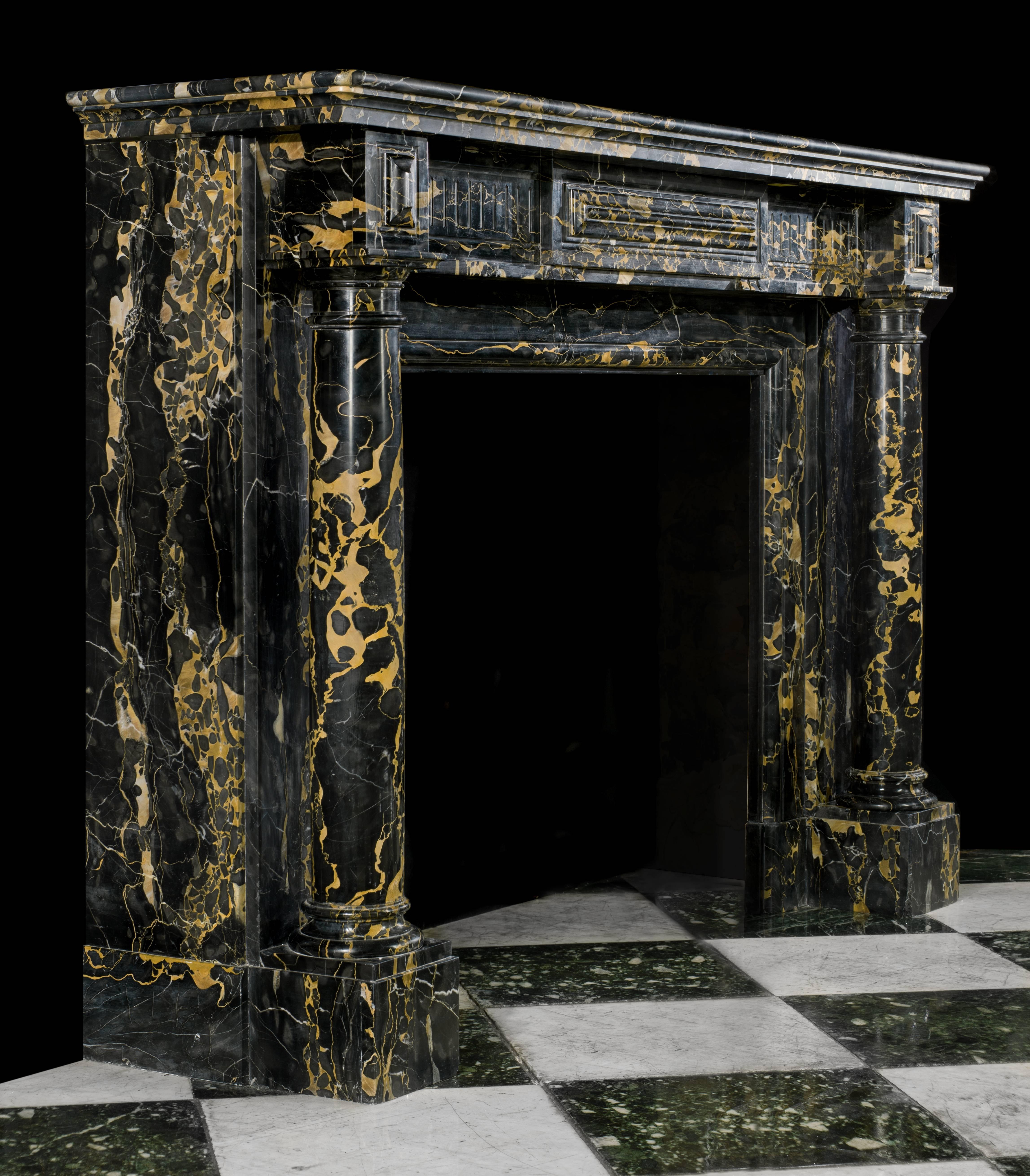 A most attractive French Regency columned antique fireplace surround in very fine black and gold veined Italian Portoro Marble. The moulded shelf is set above a fluted and cushion panelled freeze which is flanked by a pair of lozenge end blocks