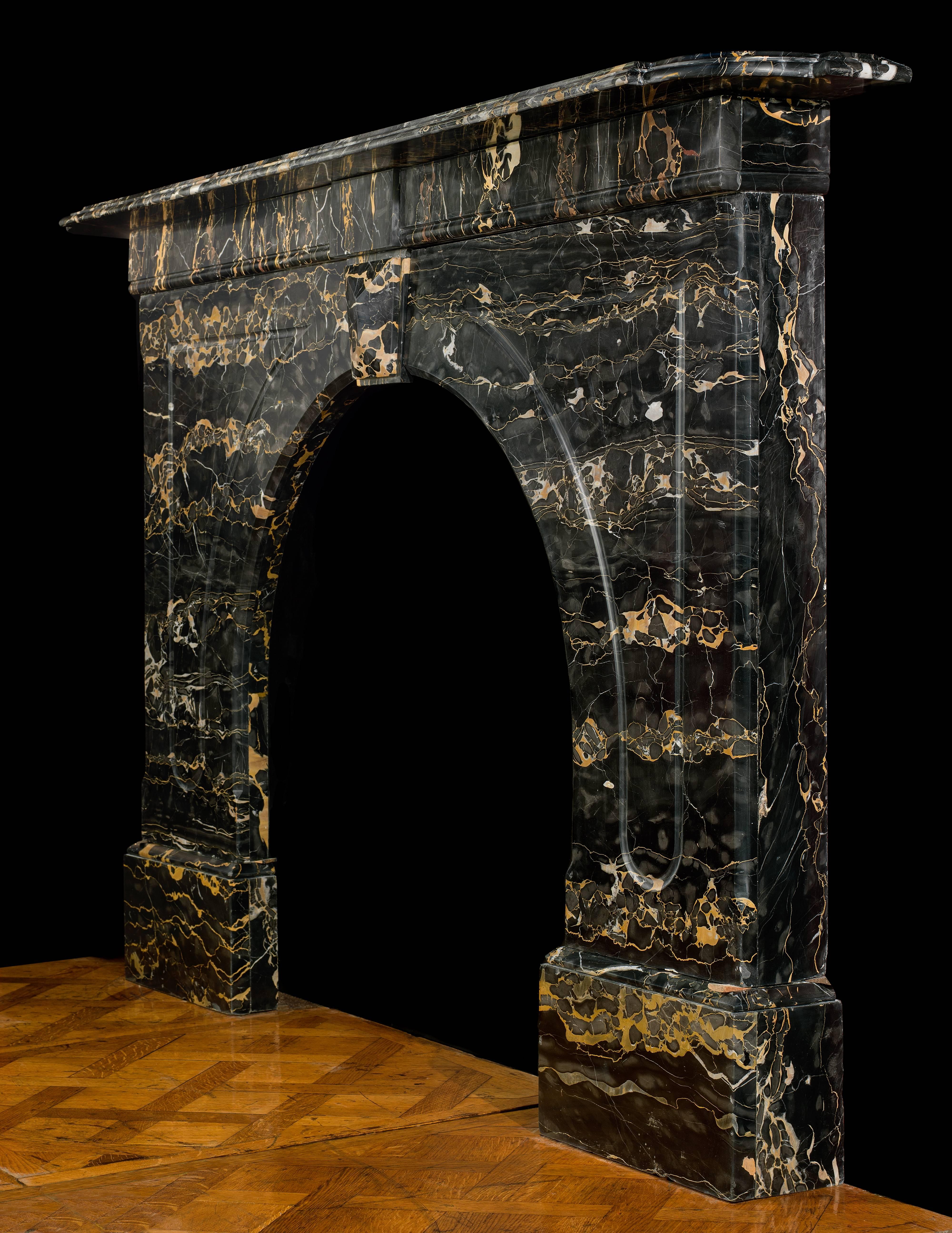 A very fine Portoro Marble antique Victorian arched chimneypiece. The moulded shelf is set above a simple panelled frieze centred by a plain panel above a keystone linking the panelled arched surround which rests on wide footblocks.
English,