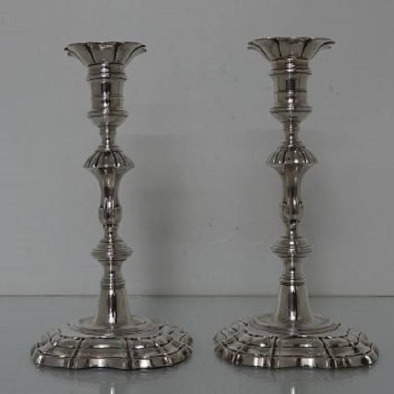 A very elegant pair of 18th century silver candlesticks, sitting on shaped square bases with sunken in wells. The columns of the sticks are stylishly formed and are crowned with a plain capital with a single band of applied strap work for