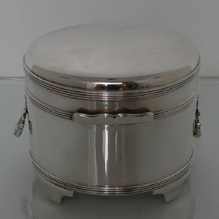 A very attractive circular hinged biscuit or sugar box plain formed in design with three bands of elegant reeding for decorative highlights. The handles of the box are drop ring and have been stylishly crafted. There are four decorative feet and a