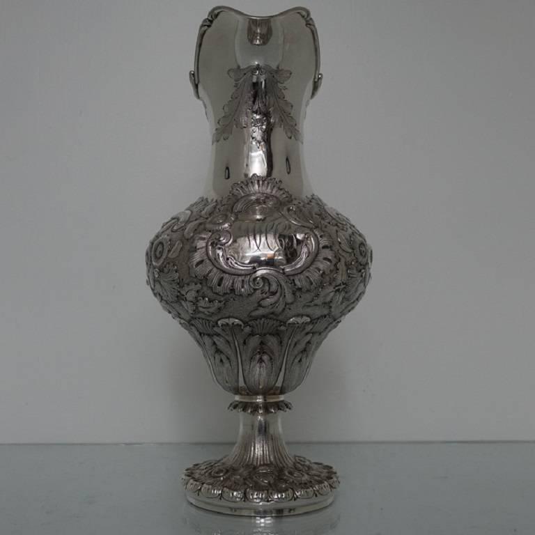 A very ornate and strikingly beautiful baluster pitcher or ewer with floral hand embossed decoration set on a matte back ground for highlights. The handle is single scroll and has acanthus leaf workmanship for decoration. The foot is of the raised