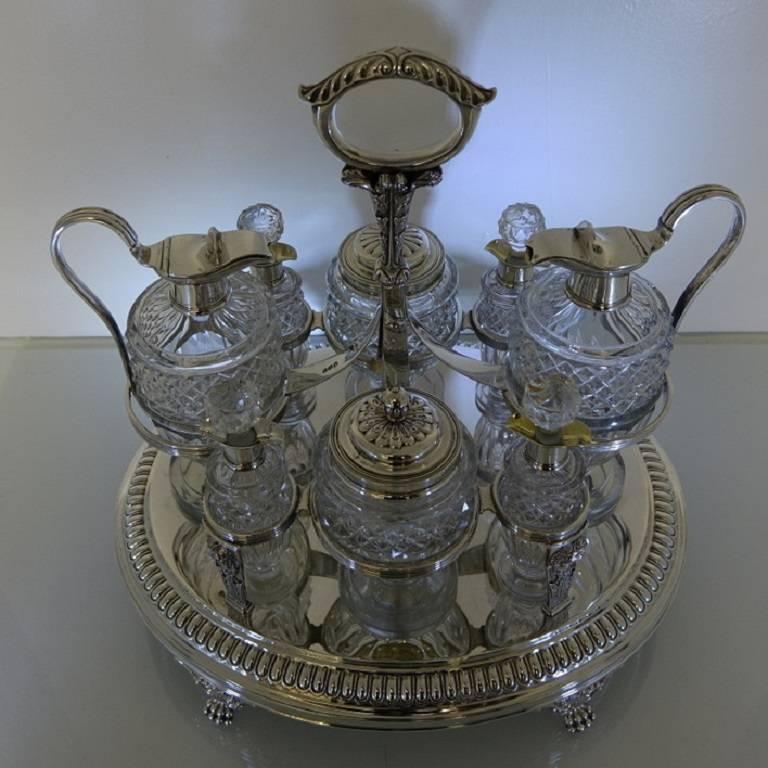 A very large and important looking silver eight bottle oval Georgian cruet. The cruet is very grand in size with a tongue border, cherubs and receded decoration and is 33cm long. The cruet has decorative claw feet and acanthus leaf handle. The glass