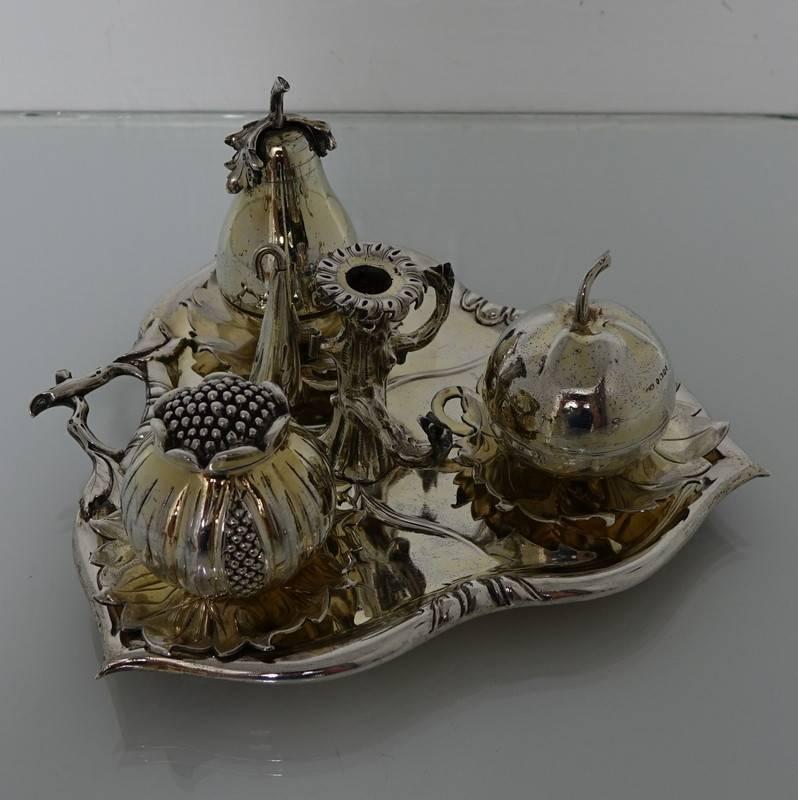 A very rare and stylish naturalistic inkstand in the form of a leaf above which sits a bell in the form of a pear, quill compartment in the form of an apple and an ink compartment in the form of a pomegranate. The centre of the inkstand has bark