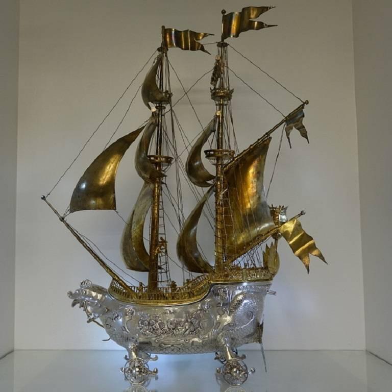 A stunningly beautiful large silver Neff/Galleon with ornate hand chasing depicting life at sea. The hull of the Neff has a serpent theme throughout with the bow baring a serpent’s face and the rudder baring a serpent’s tail. The Neff sits on four