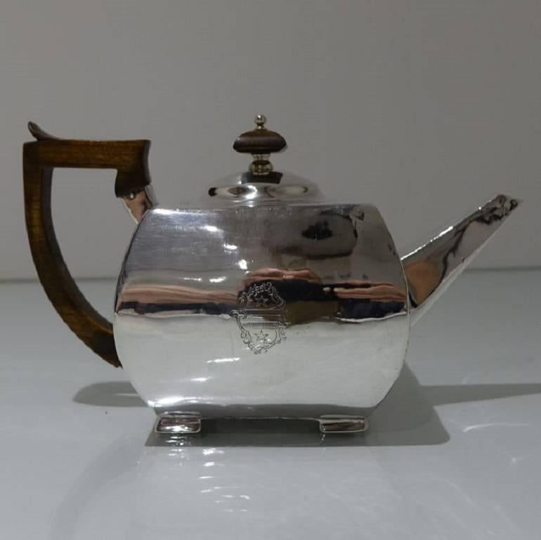 A rare and extremely stylish square shaped teapot with slight bulbous design to the body, the handle and finial are stylishly formed in fruitwood and the teapot itself sits on four elegant bracket feet. There is a double contemporary crest for
