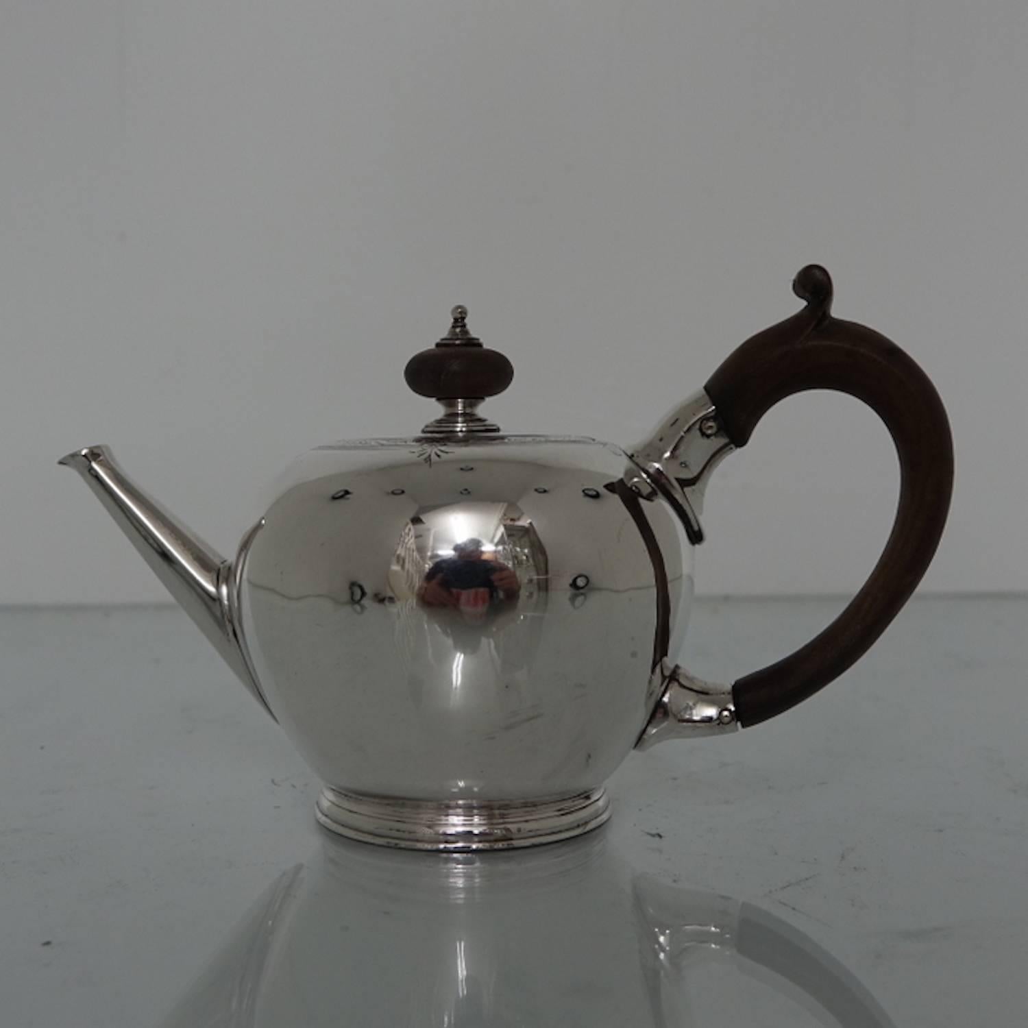 A very fine bullet teapot with a decorative single band of engraving running around the edge of the upper body. The lid of the teapot is hinged with an ebony knopped finial. The handle is also ebony and single scroll in design. The spout is
