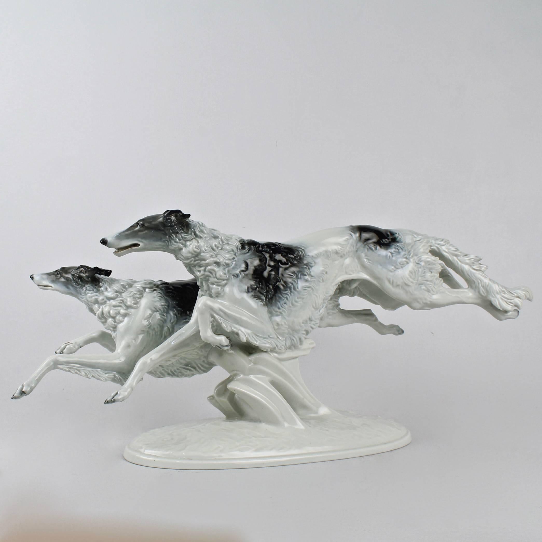 Außergewöhnlich lebhafte:: große Porzellanfigur aus dem Art déco:: die zwei Windhunde im Lauf zeigt. 

Modelliert von Max Fritz im Jahr 1934. Besetzung im Jahr 1935. 

Dekoriert mit Unterglasurmalerei in Grau auf Weiß. 

Gezeichnet für Rosenthal