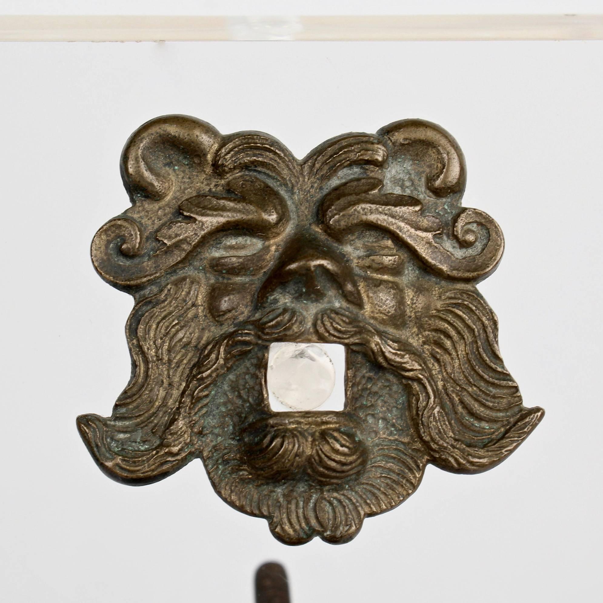A two-piece antique bronze door knocker in the Renaissance style. 

Two Hippocampi entwine to make up the knocker. Neptune's face comprises the figural escutcheon. 

The reverse has a hand peened iron bolt. (Lacks a nut.)

Mounted for display