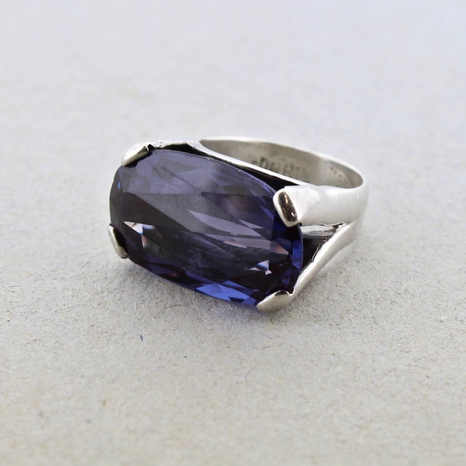 A modernist Mexican sterling silver and prong set simulated Alexandrite cocktail ring from the Doris Silver Shop in Mexico City. Very nice color change to the stone. 

Signed in shank: Doris / Mexico / 925.

Ring size: circa 6 3/4.

Items