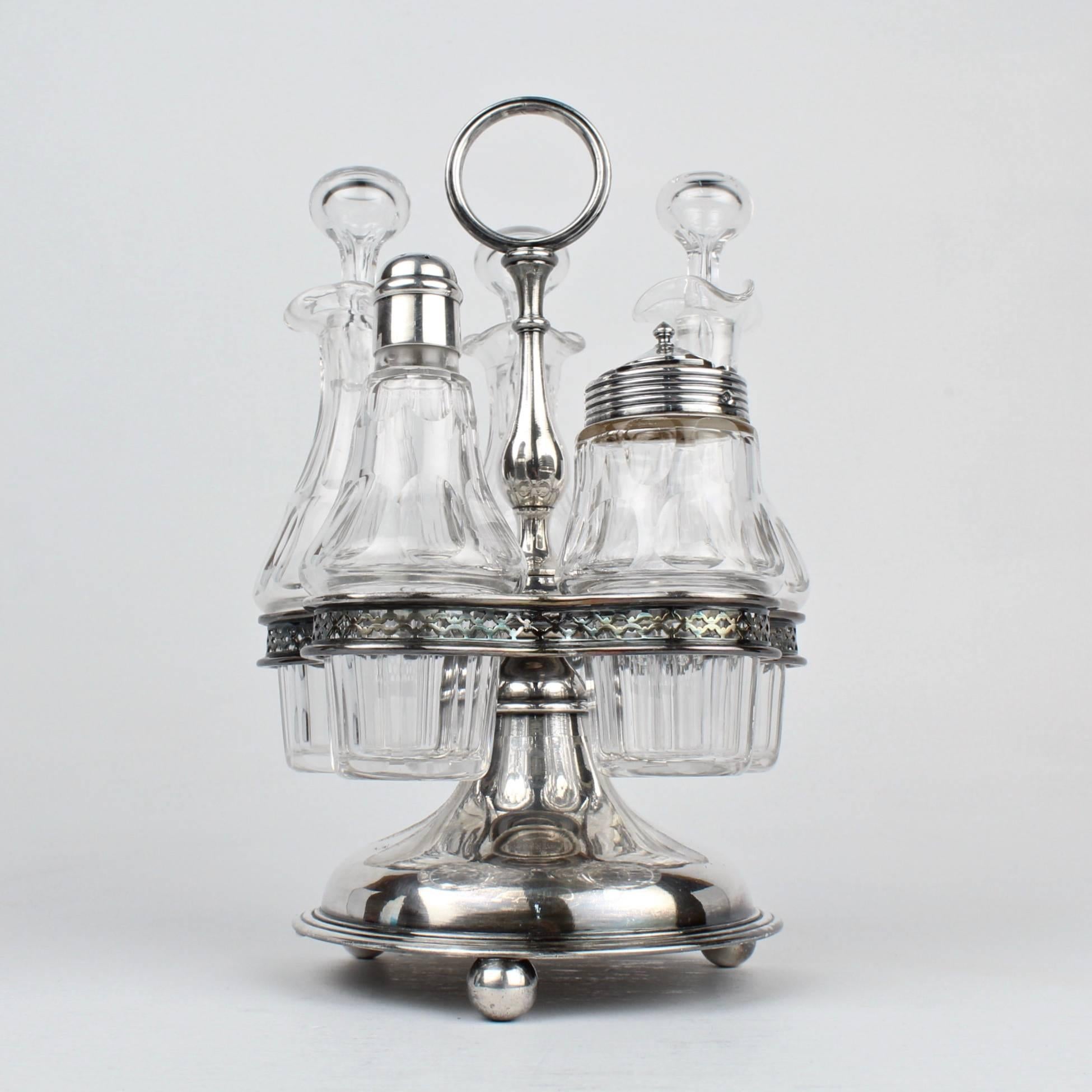 A rare Christofle cruet stand for oil, vinegar, and other condiments.

Its ball feet and a plunger base support a pierced galley that holds faceted Baccarat crystal bottles. Three bottles have stoppers, the fourth a shaker top, and the fifth is