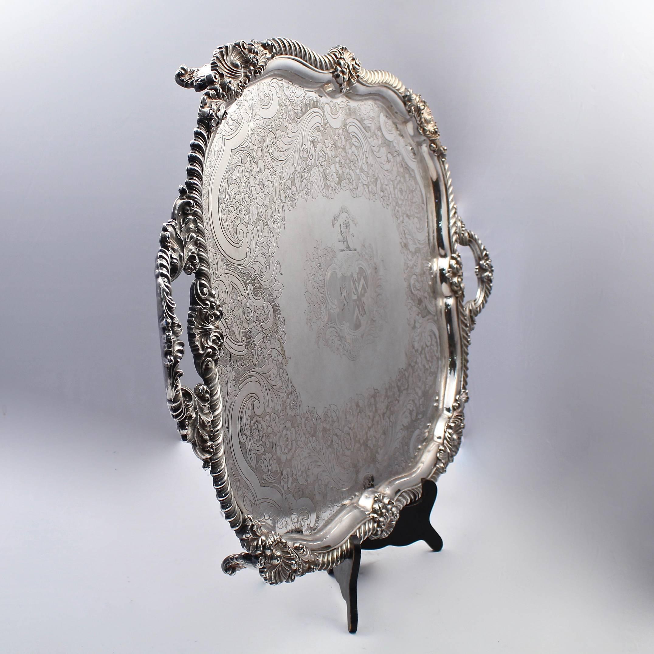 A fine and large Georgian period crested English Sheffield silver plate serving tray. 

Early 19th century. 

Supported on scroll feet with gadrooned edges and handles interspersed with shell devices. Engraved floral and leaf designs in the tray