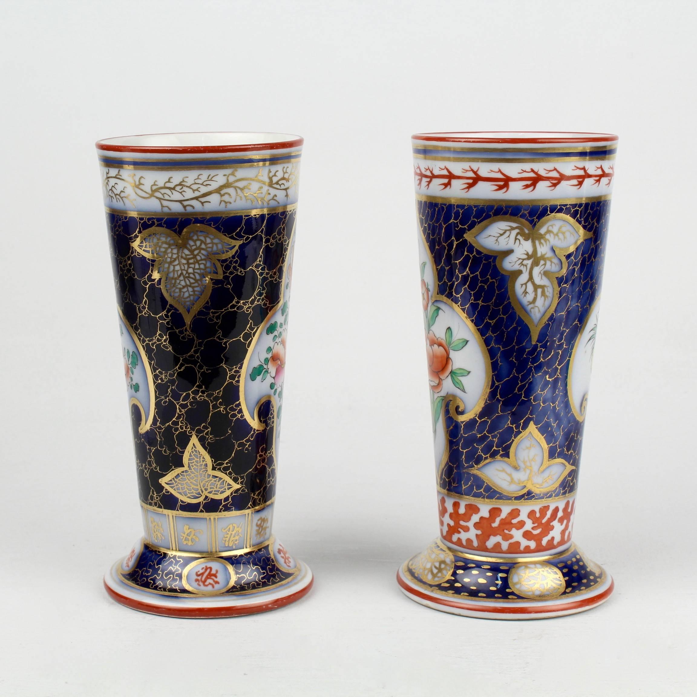 A fine associated pair of English flow blue aesthetic movement period porcelain vases with a blue ground, coral, green and gold decoration. The central cartouches have floral decorations. The remaining spaces are decorated with varying cell and