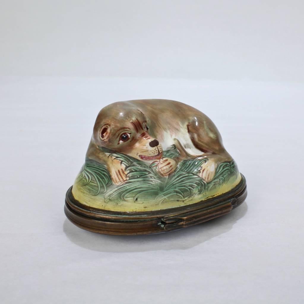 A late 18th century Bilston or Battersea enamel figural snuff box with a recumbent pug. 

The dog rests curled atop a grassy patch on the lid. 

Terrific decorative whimsy in what was a period 