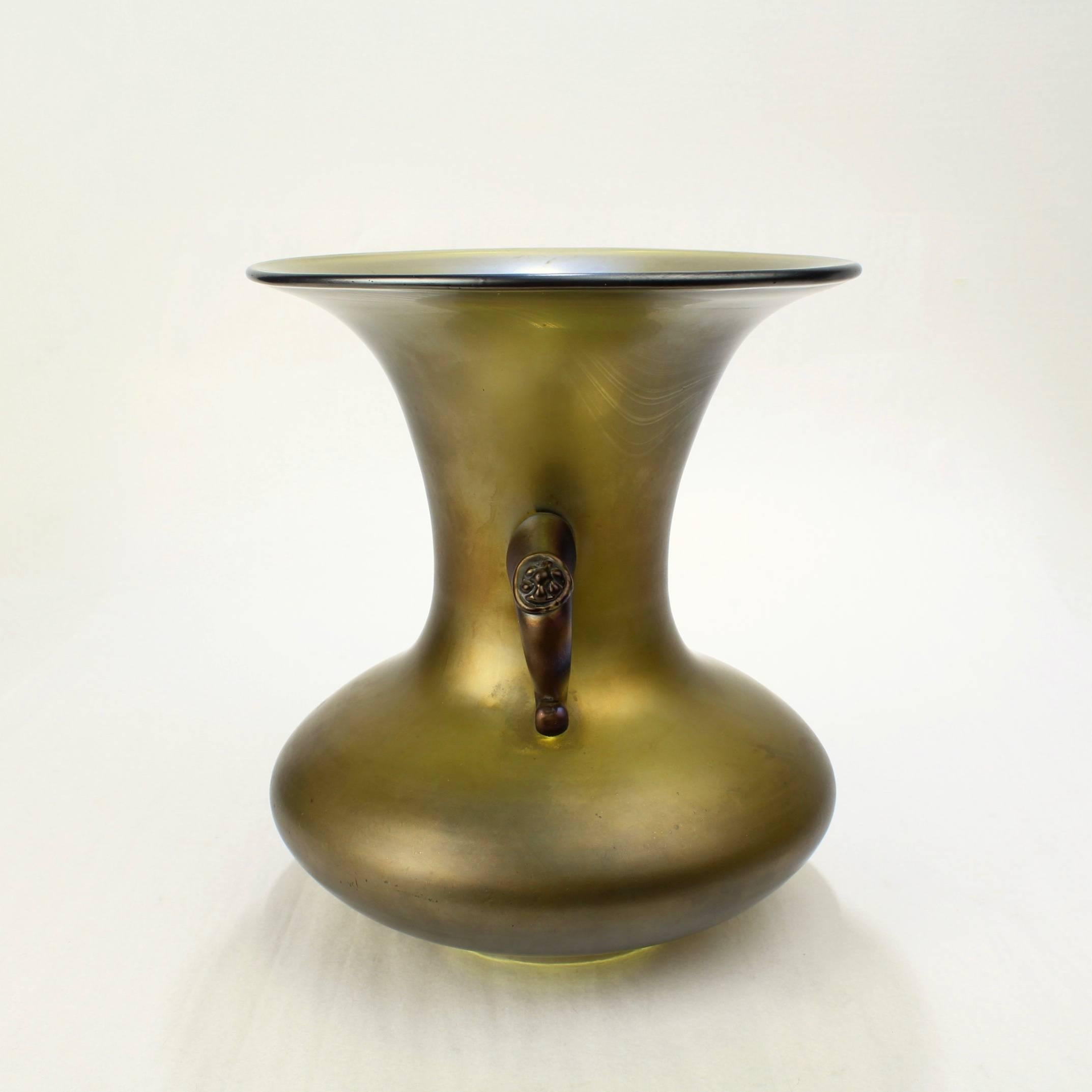 A good antique Loetz vase with an early bronze or bronce glatt iridescent finish.

With applied handles with button knops.

The form inspired by early Japanese design. 

Height: ca. 7 3/4 in.

Items purchased from David Sterner Antiques must