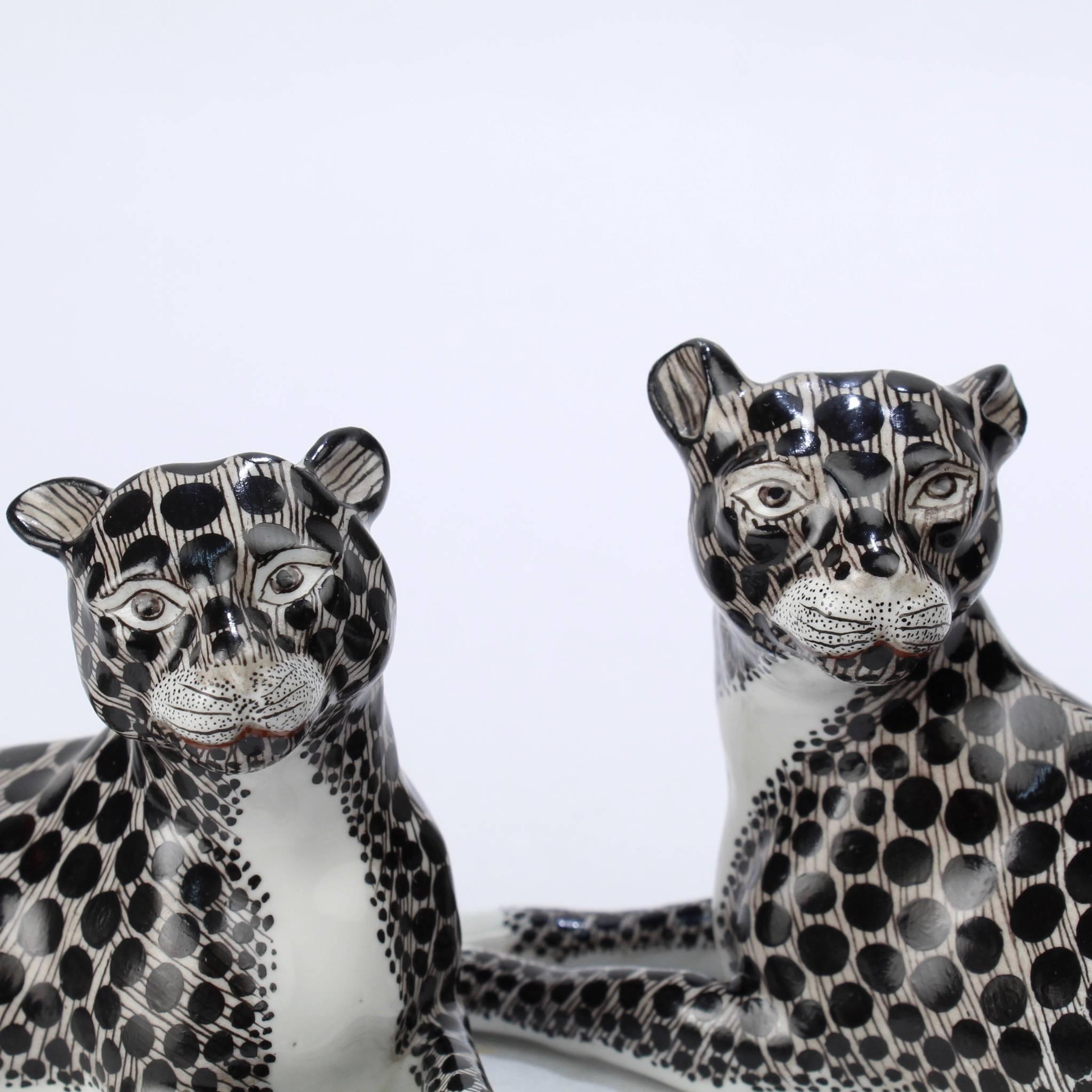 A fine and rare pair of snow leopard figurines by Samson & Cie of Paris.

Fine stylized big cats with large black spots throughout. 

Marked on the reverse with the blue underglaze crosses lines factory mark.

Length of larger cat: circa 6 3/4