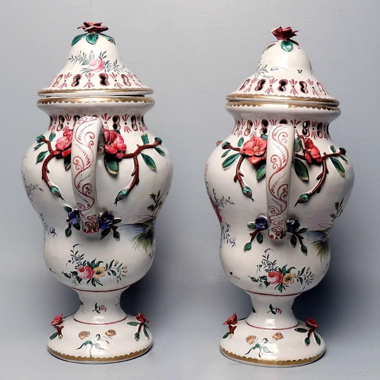 A pair of large Veuve Perrin French Majolica lidded urns or vases.

Each decorated with flowers on one side and a hunting and fishing scene on the reverse.

Height: circa 17 1/2 in.

Items purchased from David Sterner Antiques must delight