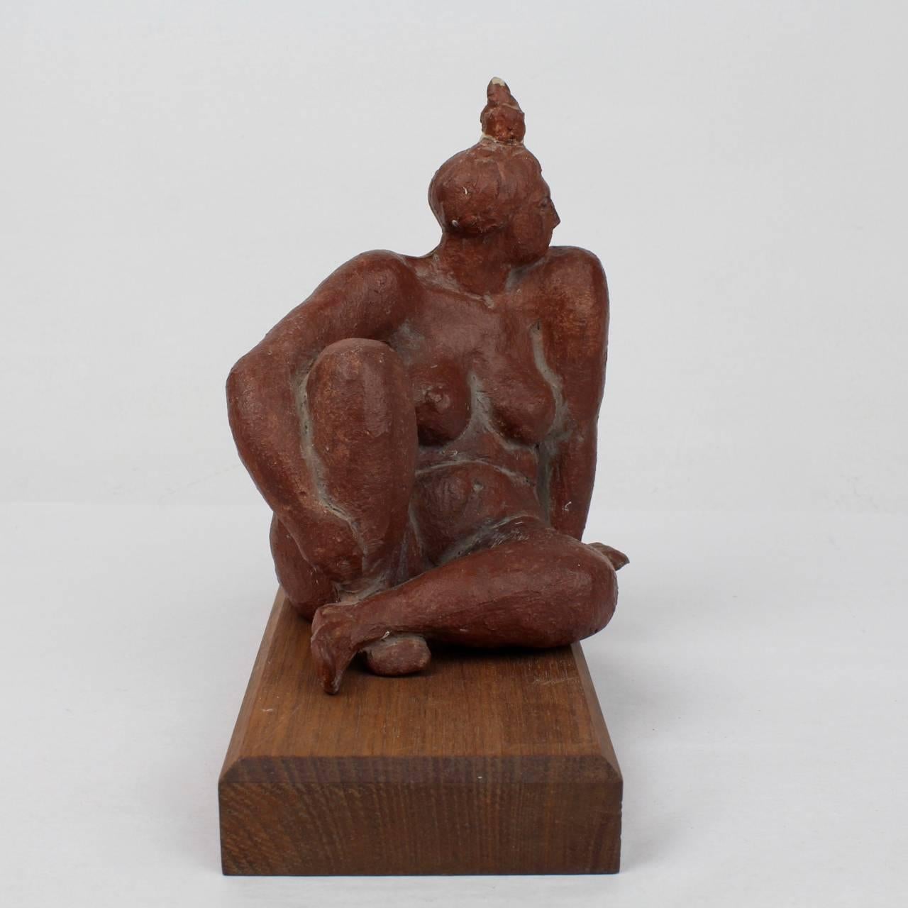 A good, modernist terracotta sculpture of a plump seated woman. 

Terrific whimsy and style. Placed on a wooden block and finished in a brown-red wash.

Signed 'F. Kahn' and “86” to reverse.

Height: ca. 5 1/2 in. (w/o block.)

Items