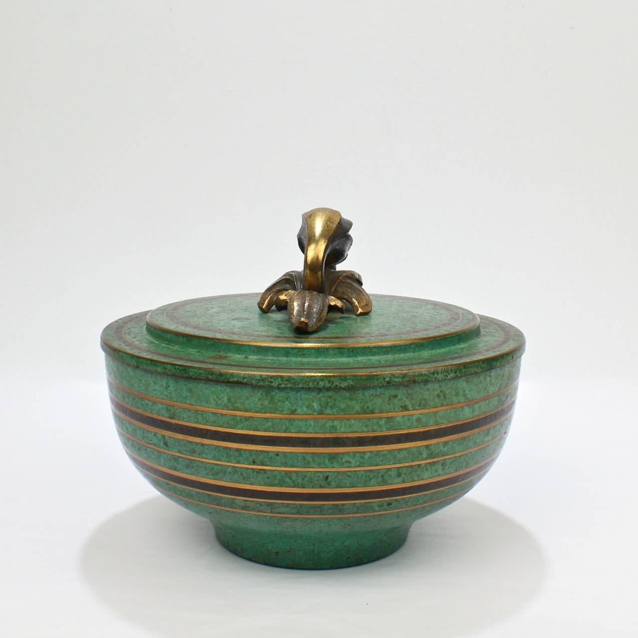 A rare, larger-scale Carl Sorensen covered bronze bowl.

With his typical verdigris finish, vertical stripes, and a stylized floriform bronze finial. 

Base marked with CS, Bronze, Carl Sorensen and 1091.

Diameter: ca. 7 1/2 in.

Items