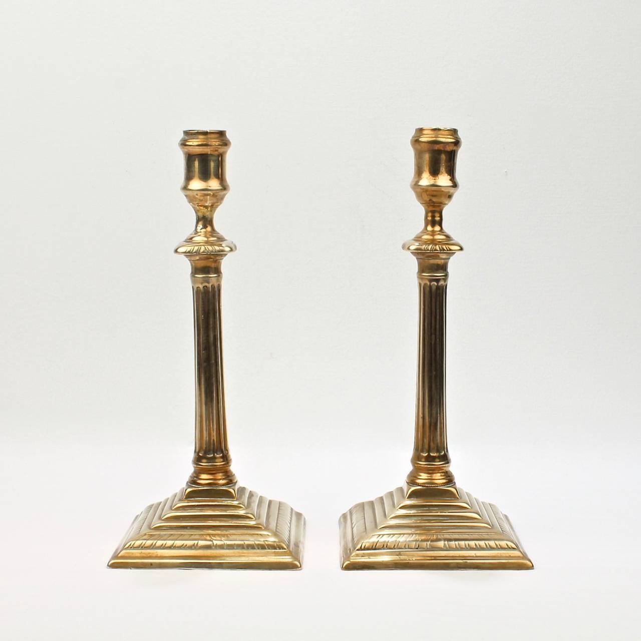 A fine pair of George III neoclassical brass candlesticks.

With gadrooned and stepped bases and columnar shafts supporting urn form candle cups.

With shafts peened through the bases and casting seams to sides.

Height: ca. 10 1/4