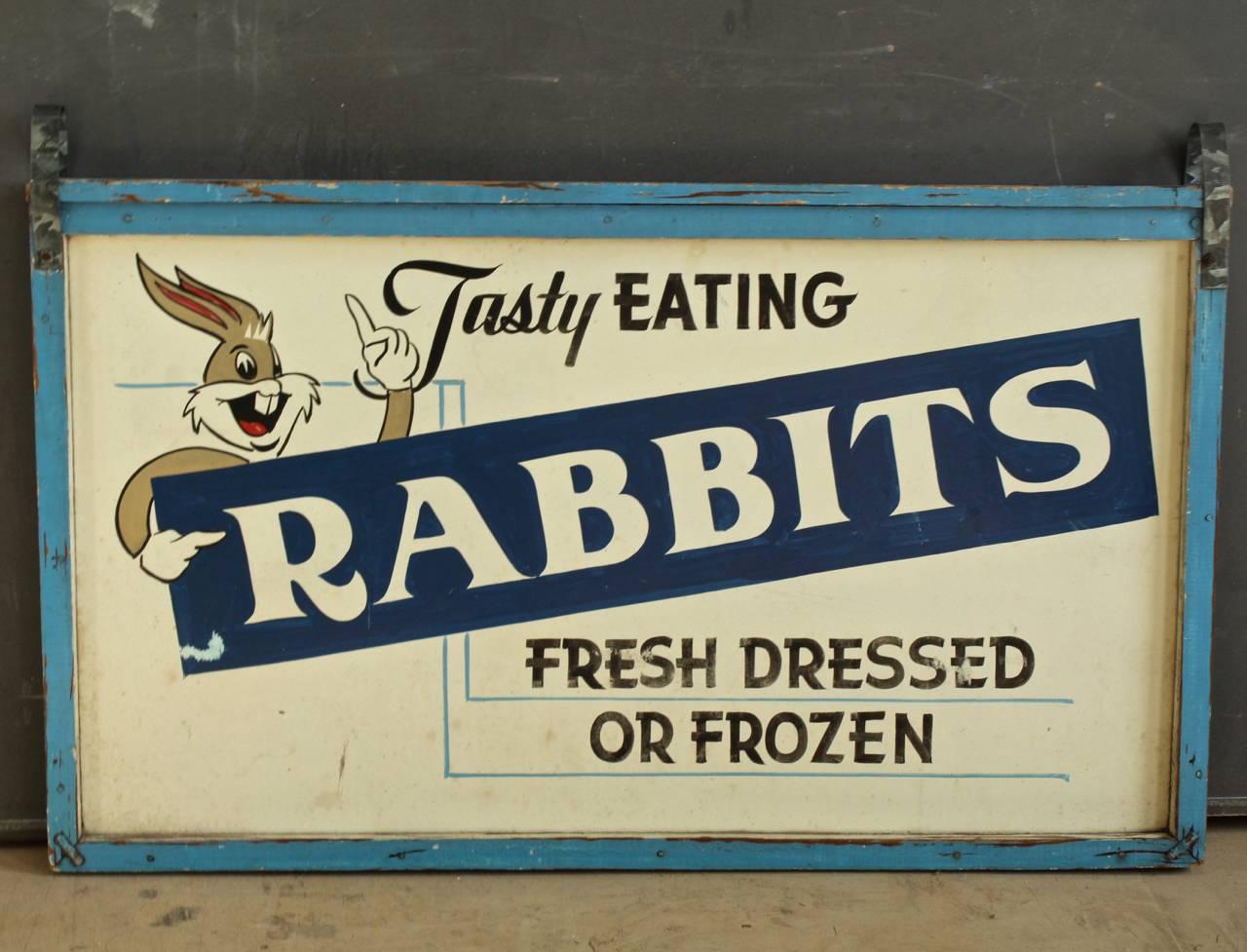 A mid-20th century folky trade sign that is very much to the point!

With a painted - Tasty Eating Rabbits: Fresh Dressed or Frozen - and a stylized Bugs Bunny character pointing.

Comprised of blue and white painted panel mounted in a wood