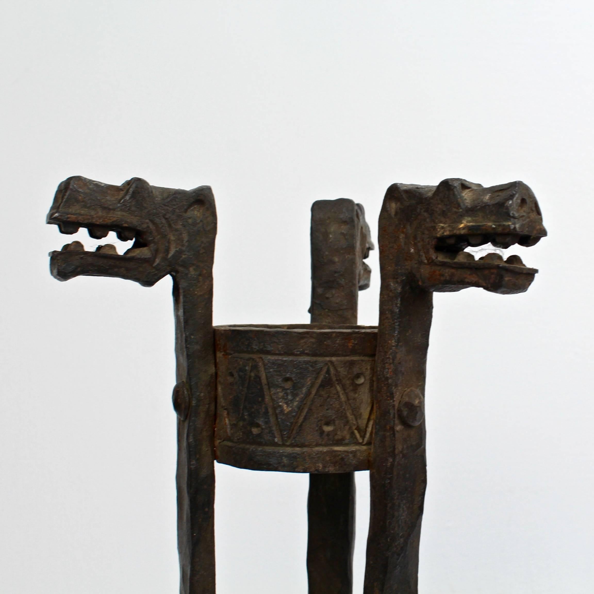 A good pair of Neo-Gothic wrought iron stands in the style of Samuel Yellin.

Each with dragon head finials, paw feet, and two worked central rings supports.

We think that these are either intended for use as Amphora form vase stands or as