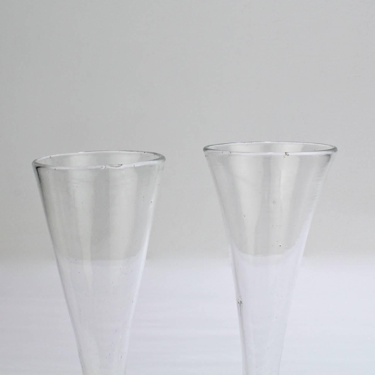 A fine, near pair of Georgian III Anglo-Irish glass champagne flutes.

Two fine handblown examples with conical flutes supported on a stems with angular knops and a wafer feet. Each with charming signs of handmade production and polished Pontil