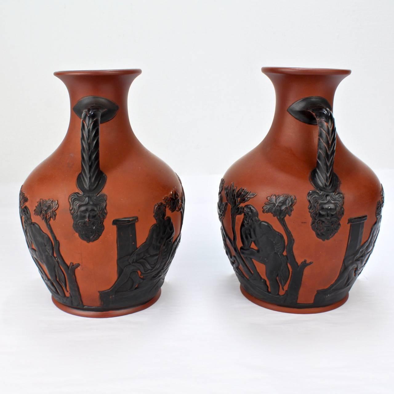 A good pair of Wilhelm Schiller and Son terra cotta or earthenware Portland vase copies in orange and black.

Modeled after Wedgwood's famous copy of the ancient Greek cameo glass vessel known as the Portland vase.

Wilhelm Schiller and Son were