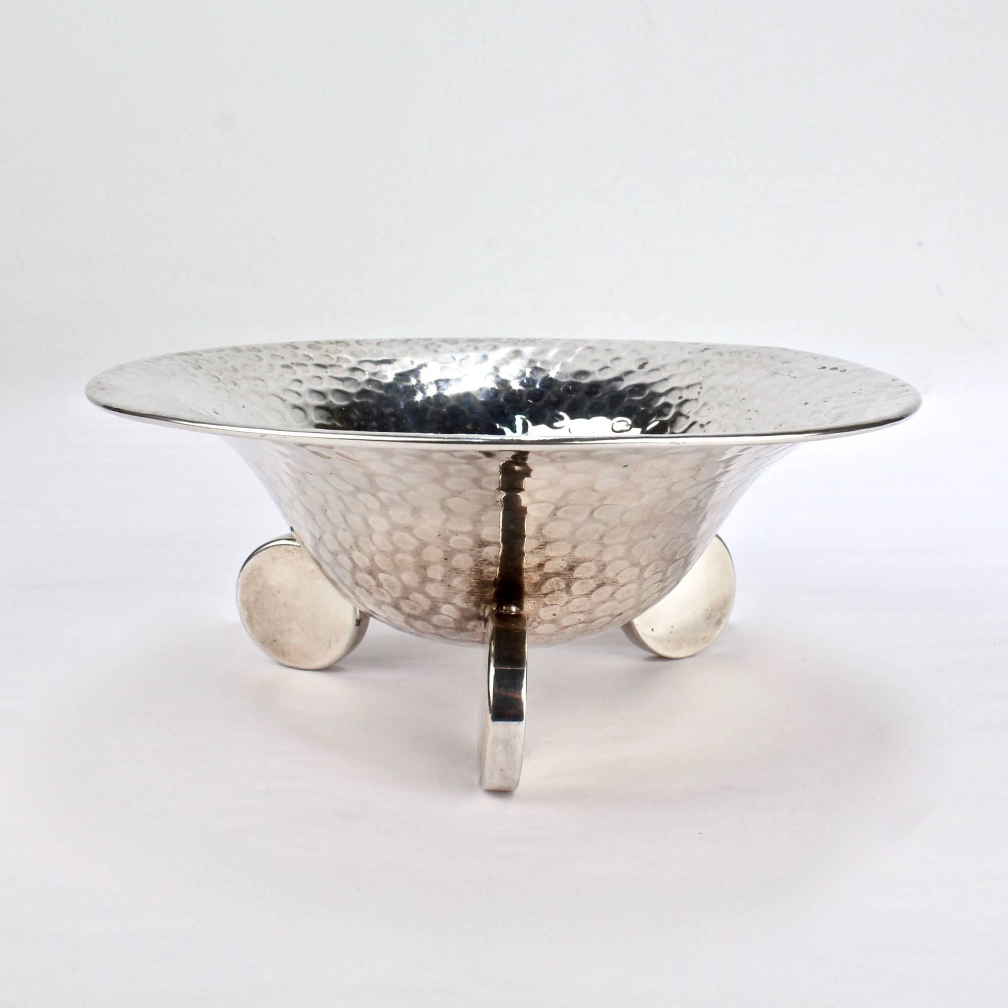 A fine Art Deco 800 silver bowl.

With hand-hammered bowl supported by three disc-shaped tab feet. 

Interior rim hallmarked for .800 silver fineness, Krakow Poland, and with WH maker's mark.

Measure: Diameter ca. 6 3/8 in.
Weight ca. 180