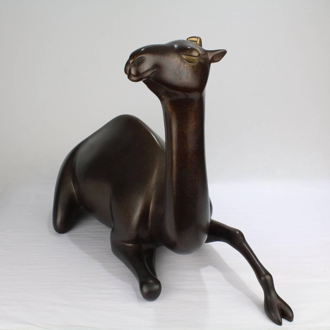 A large limited-edition recumbent camel bronze sculpture by Loet Vanderveen.

With a fantastic, wry expression on the camel's face and a two-tone patina.

Etched signature, copyright, and edition no. 9/350 to the base.

Width ca. 23