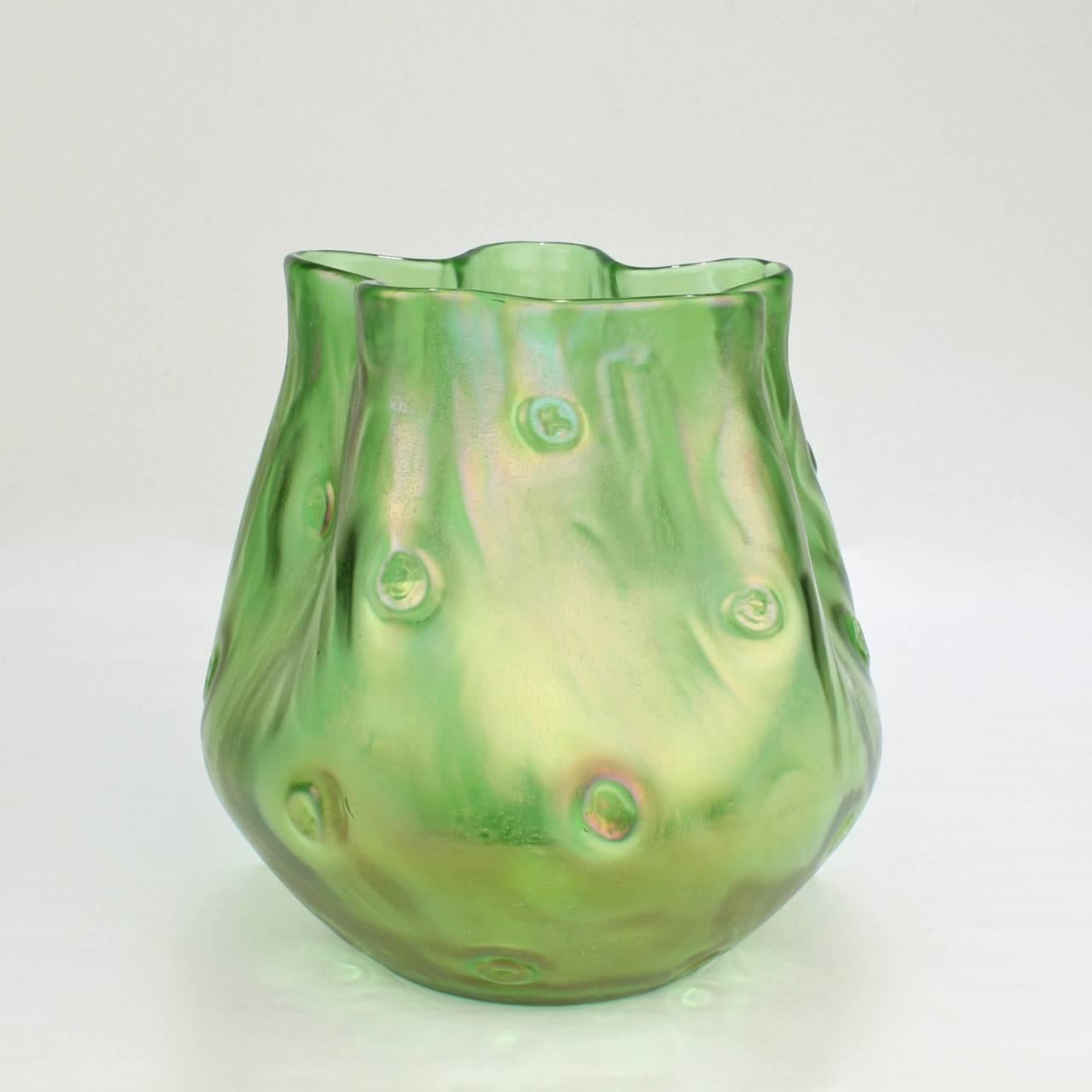 A well-scaled Loetz Crete Rusticana pattern art glass vase with a green iridescent finish.

Its Art Nouveau or Jugenstil form mimics an organic knotty wooden surface with a cinquefoil pinched lip and a polished pontil base. 

Measures: Height: