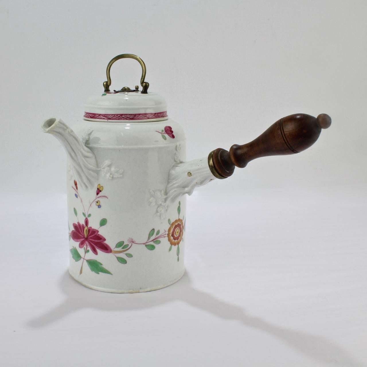 A good marcolini period Meissen Porcelain chocolate pot.

This rare chocolate pot is decorated in an Indian flower variant in purple, green, yellow and blue and retains a period wooden handle. The lid has a brass handle, mount, and spoon hole